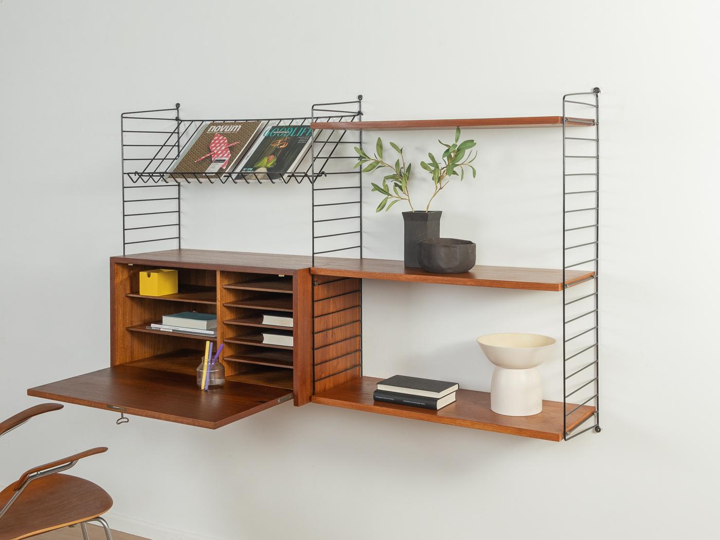 Original String shelf designed in 1949 by Nils Strinning in teak veneer. The system consists of three metal ladders in black with four shelves, one magazine rack and one foldable container.

This original String shelf is much better processed and of