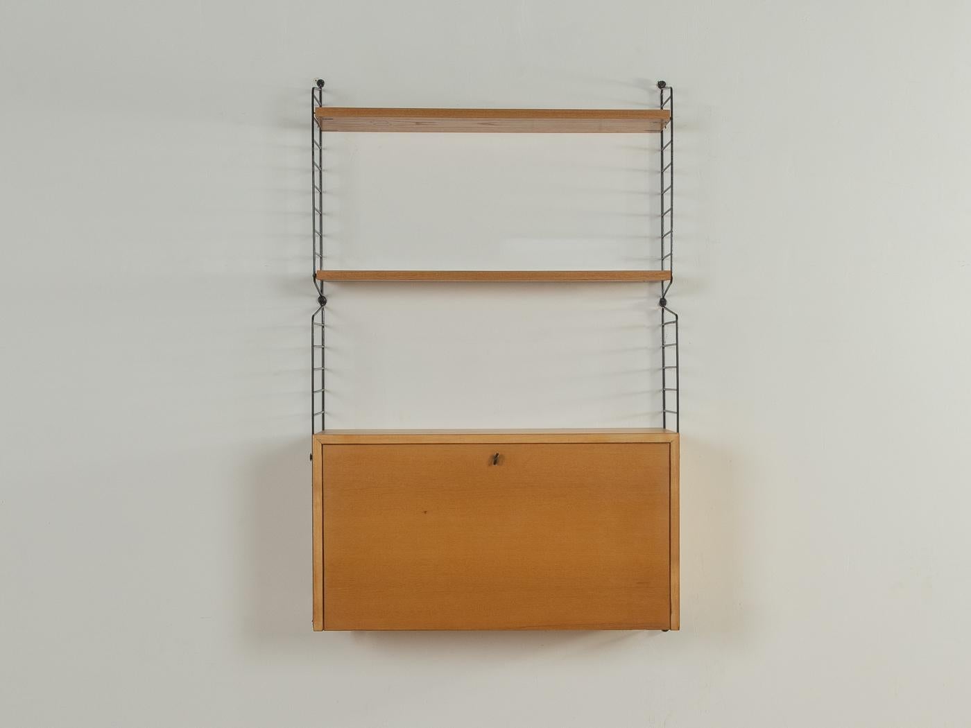 Scaffale originale String disegnato nel 1949 da Nils Strinning in impiallacciatura di frassino. Il sistema è composto da quattro scale in metallo di colore nero con due ripiani e un contenitore con porta a battente e diversi scomparti.

Questa