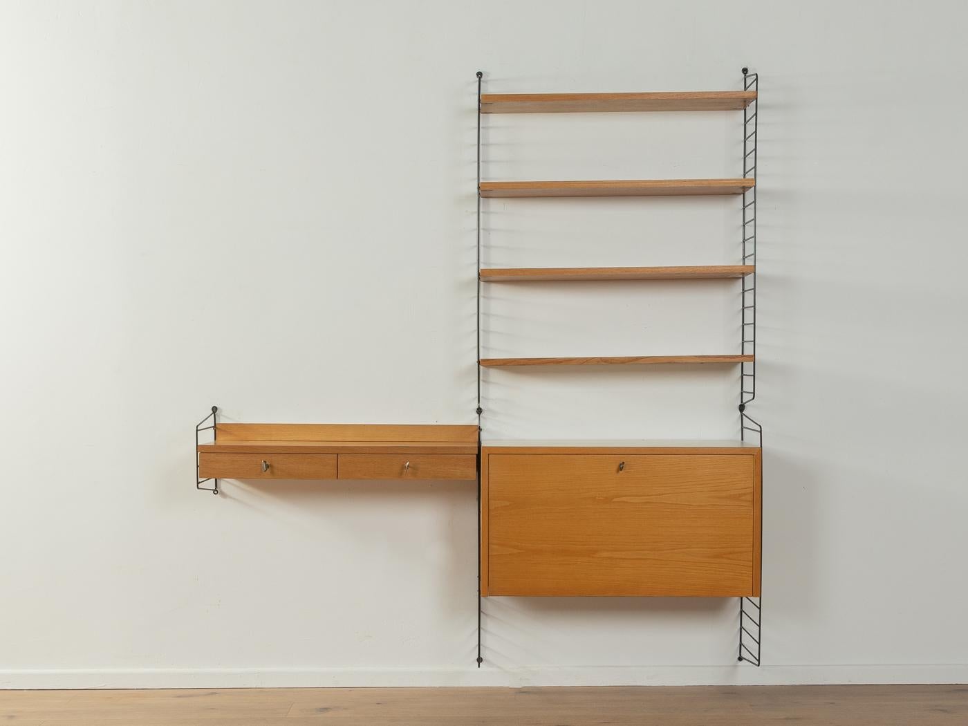 Scaffale originale String disegnato nel 1949 da Nils Strinning in impiallacciatura di frassino. Il sistema è composto da cinque scale in metallo di colore nero con quattro ripiani, un contenitore con due cassetti e un contenitore con porta a