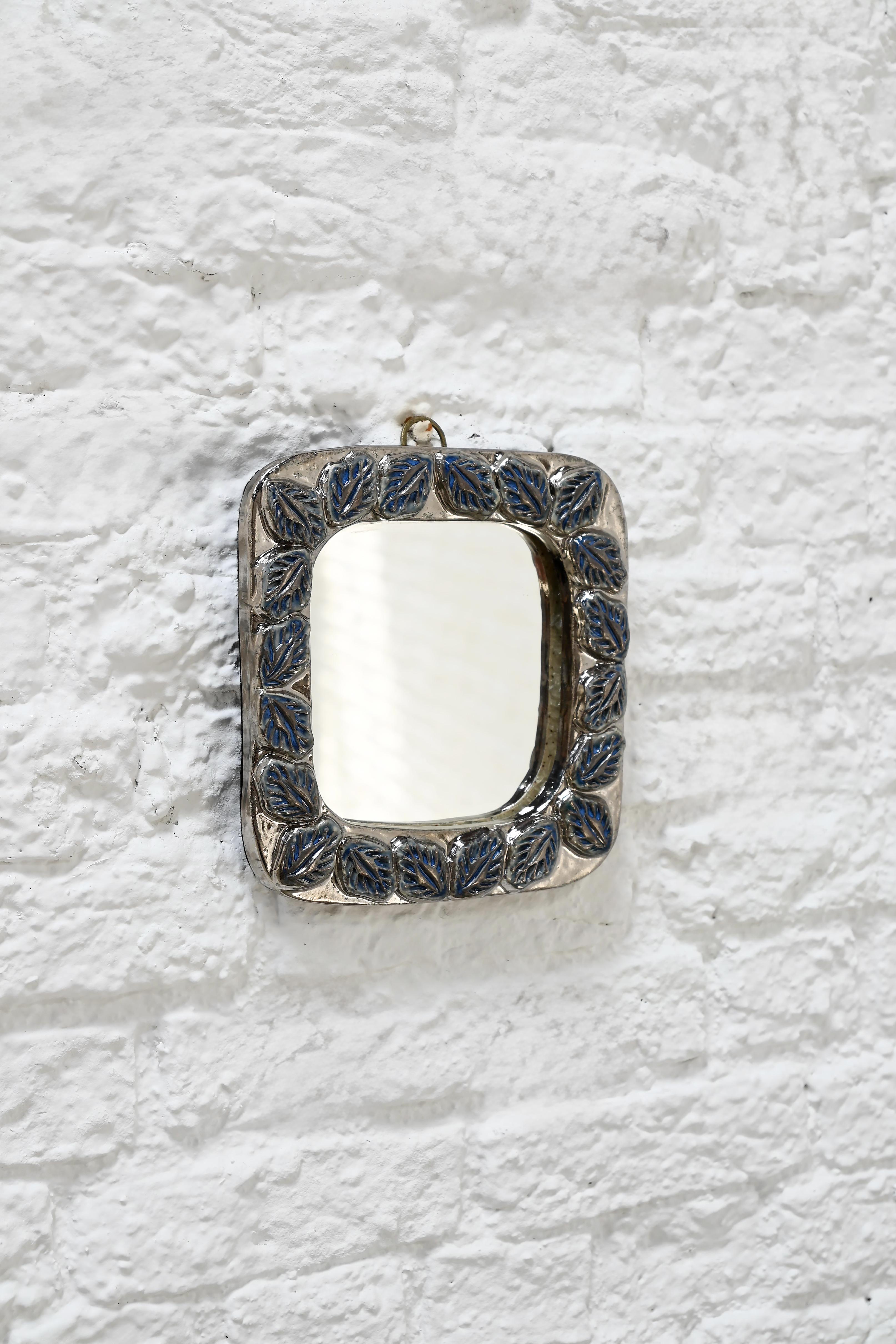 This charming artisanal square mirror features deep blue ceramic leaves set in a silver-toned frame, giving it a rich, textured look. The design has a subtle botanical feel, very reminiscent of Mithe Espelt’s mid-century work from France. Howerever