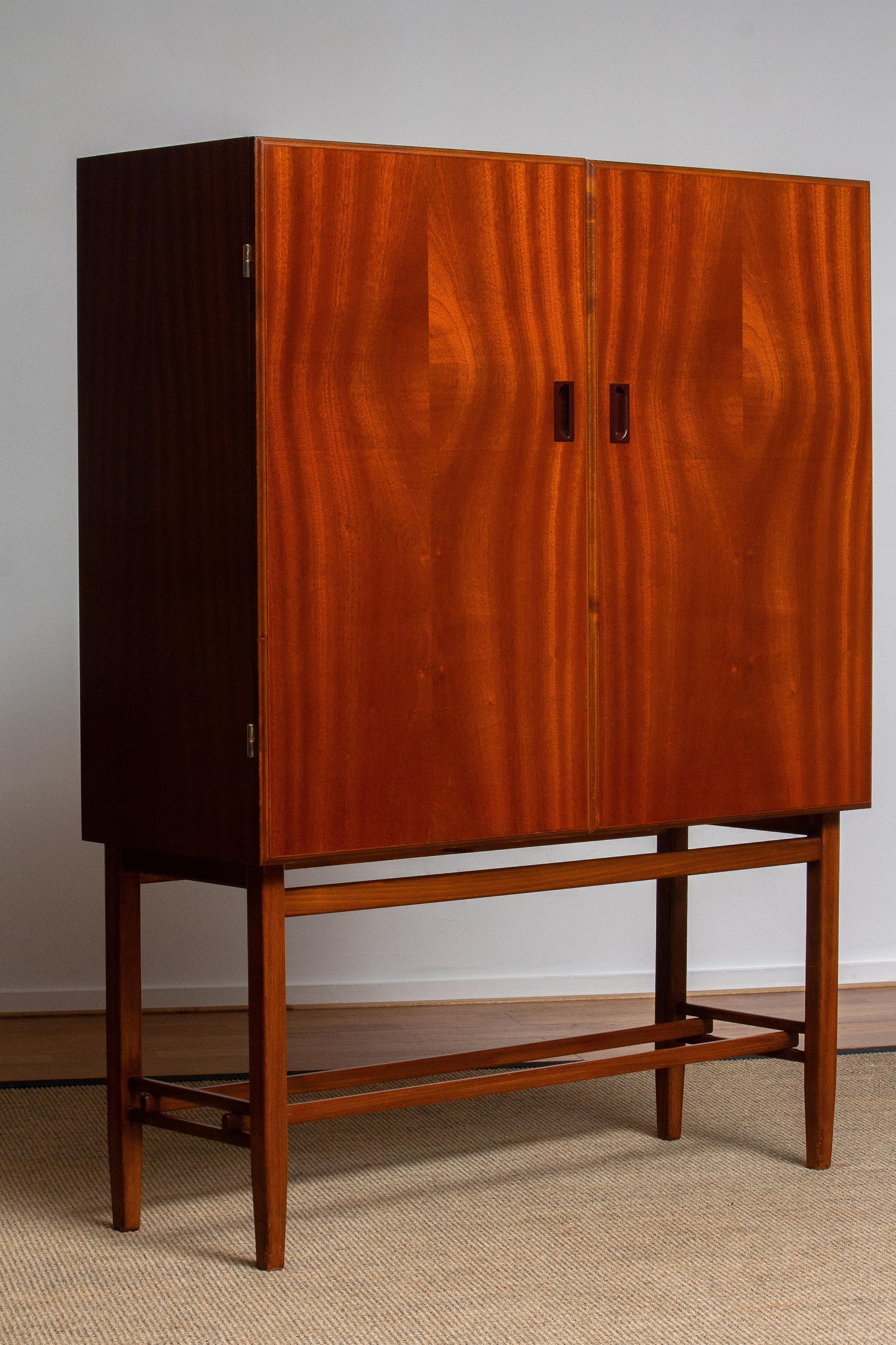 Beautiful dry bar / cabinet in mahogany made in Sweden, by Forenades Mobler of Linkoping, 1950s.
Equipped with two doors with behind two drawers and two adjustable shelves.
Standing on slim and tall legs.

The overall condition is very good.