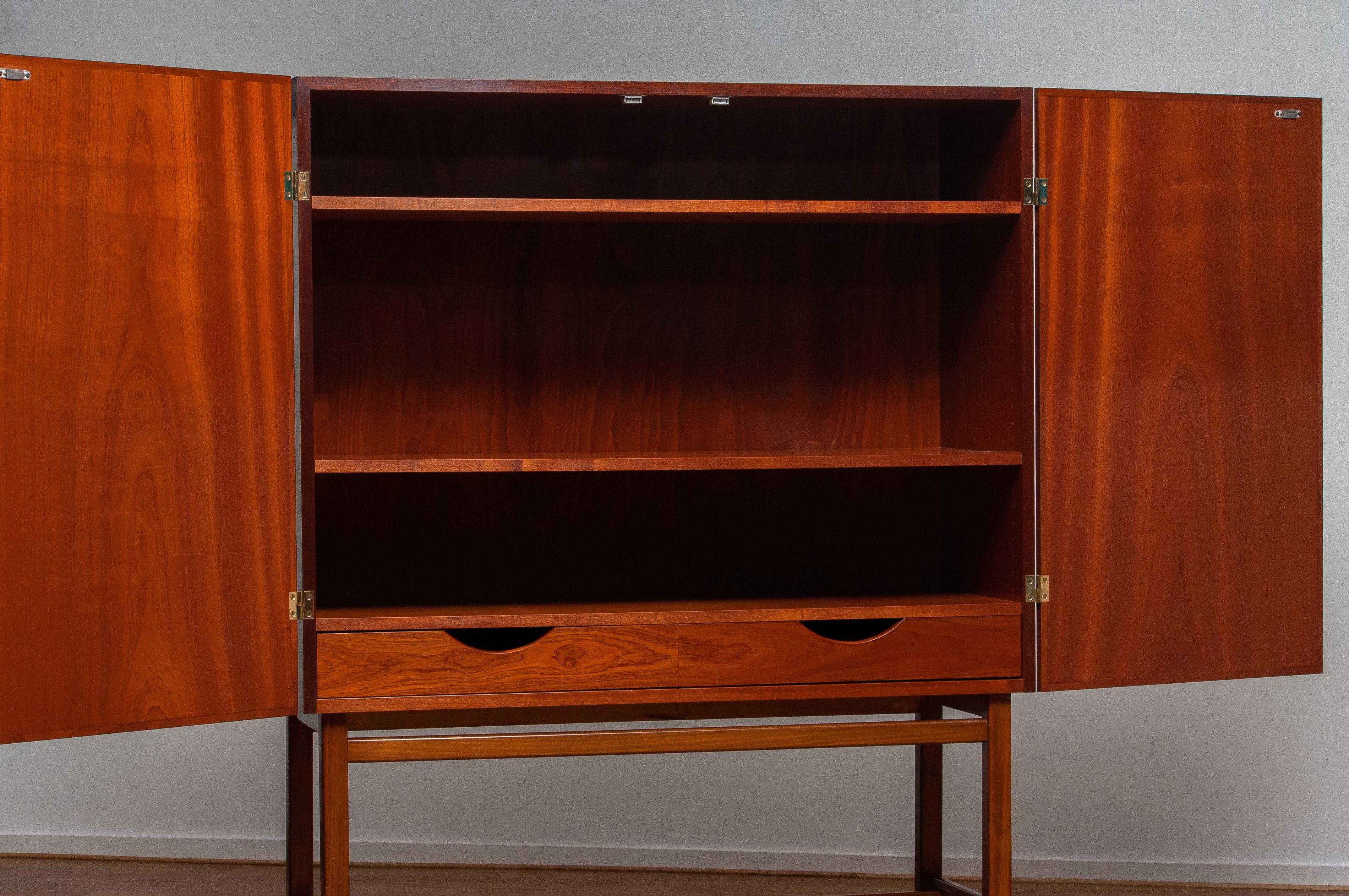 Beautiful dry bar / cabinet in mahogany made in Sweden, by Forenades Mobler of Linkoping, 1950s.
Equipped with two doors with behind two drawers and two adjustable shelves.
Standing on slim and tall legs.

The overall condition is very good.