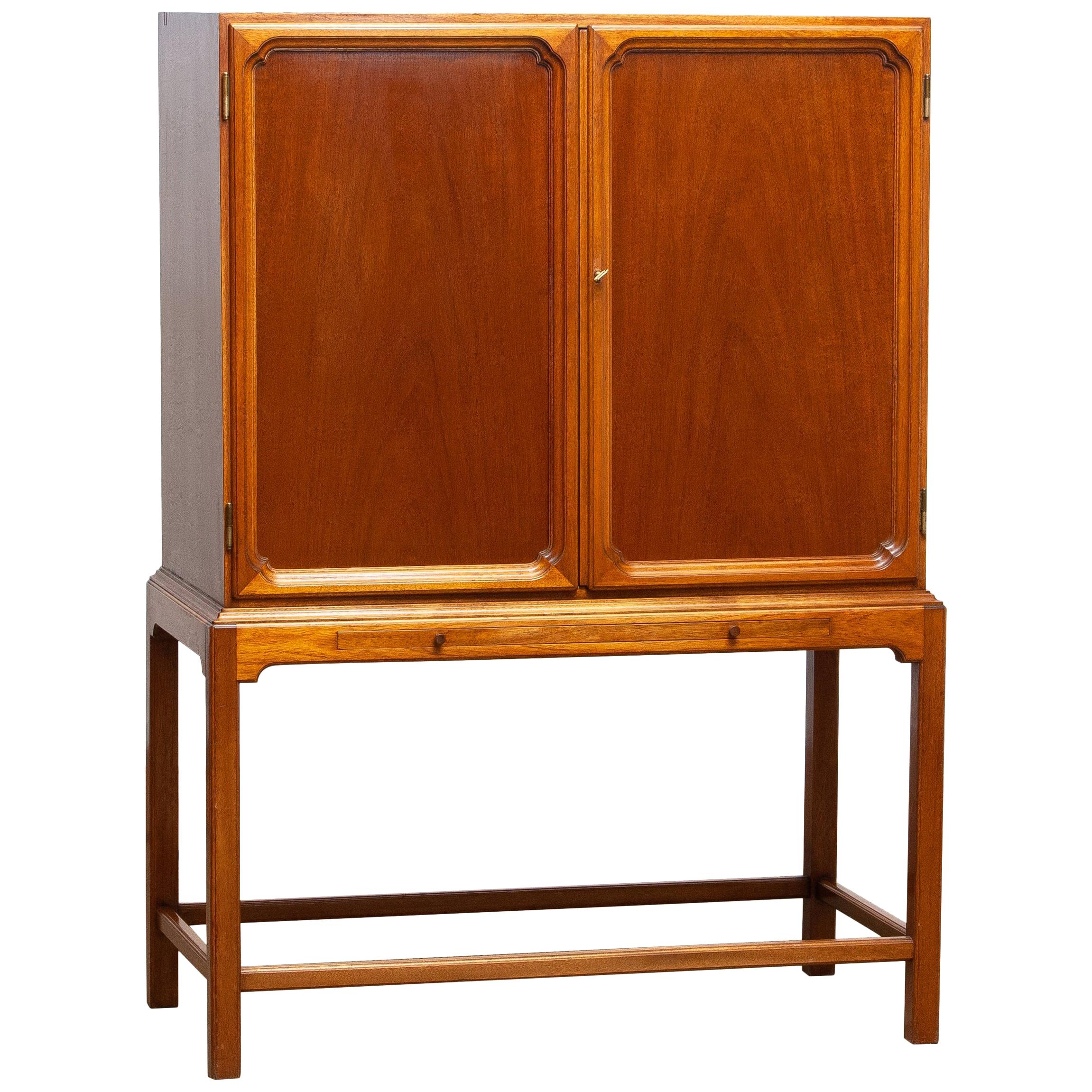 Beautiful dry bar / cabinet in mahogany on tall slim legs made in Sweden, 1950s.
Equipped with two lockable doors with behind four drawers and shelves. The shelves and rear are decorated with glass mirrors. Also an extendable shelf at the front
