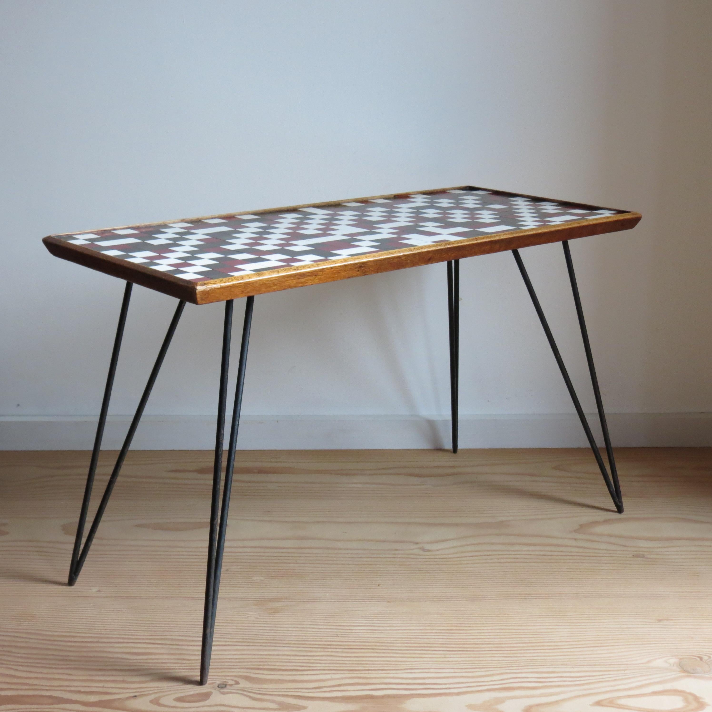 Wonderful mid-century side table dating from the 1950s. Handmade, with hand cut mosaic Formica top, onto a Mahogany top and metal steel rod hairpin legs.

Very nicely handmade, originates from the 1950s.  Red white grey and black Formica cut into