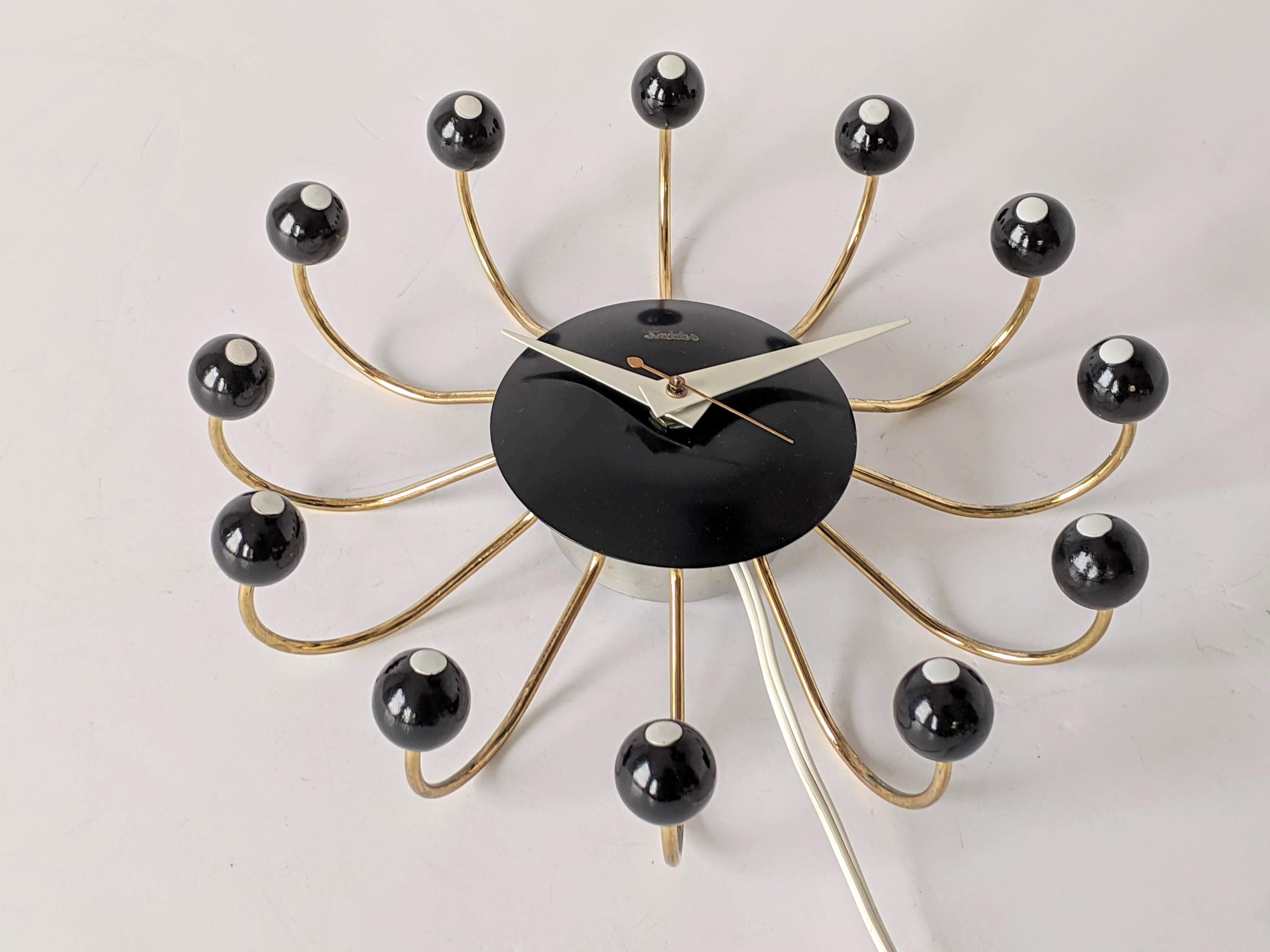 Iconic and rare snider spider electric wall clock Model 500.

Enameled black hand turned wood ball on a brass plated frame.

Well made clock with quiet operating motor. Keep time accurately.

4 feet of wire with wall plug.

 