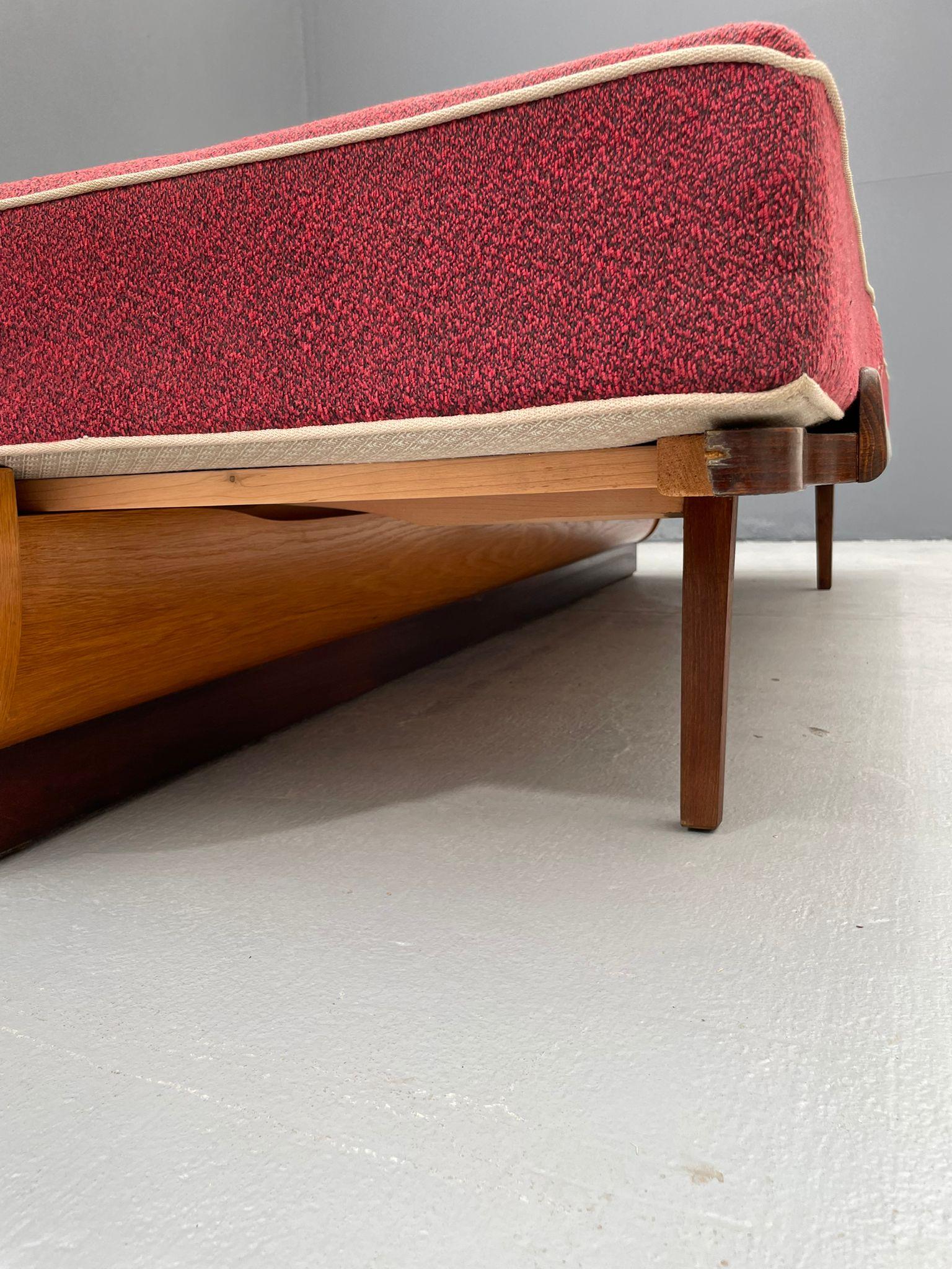 This convertible sofa bed was designed by Jindřich Halabala and produced in the 1950s by UP Závody Rousínov, Pozořice factory, as confirmed by the original factory label. The piece features a veneered wooden base, upholstered seat and back cushions,