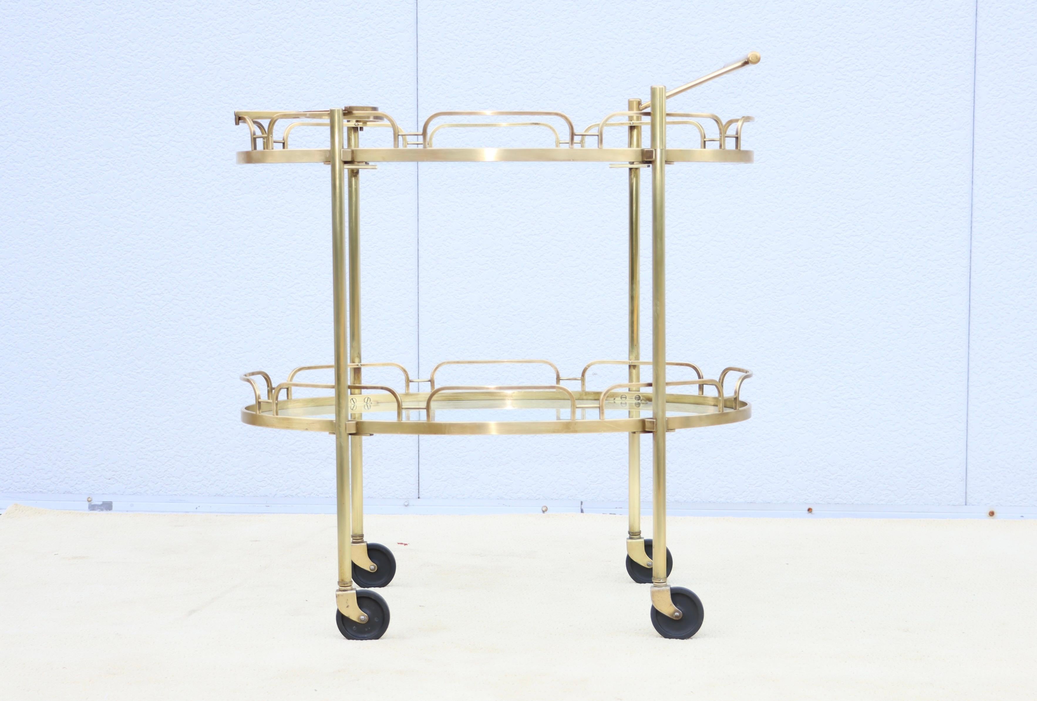 Amazing 1950's solid brass two tier oval brass bar cart by Maxwell Phillips, with removable handle and original bottle holder, in vintage condition lightly hand polished with some wear and patina to the brass due to age and use.