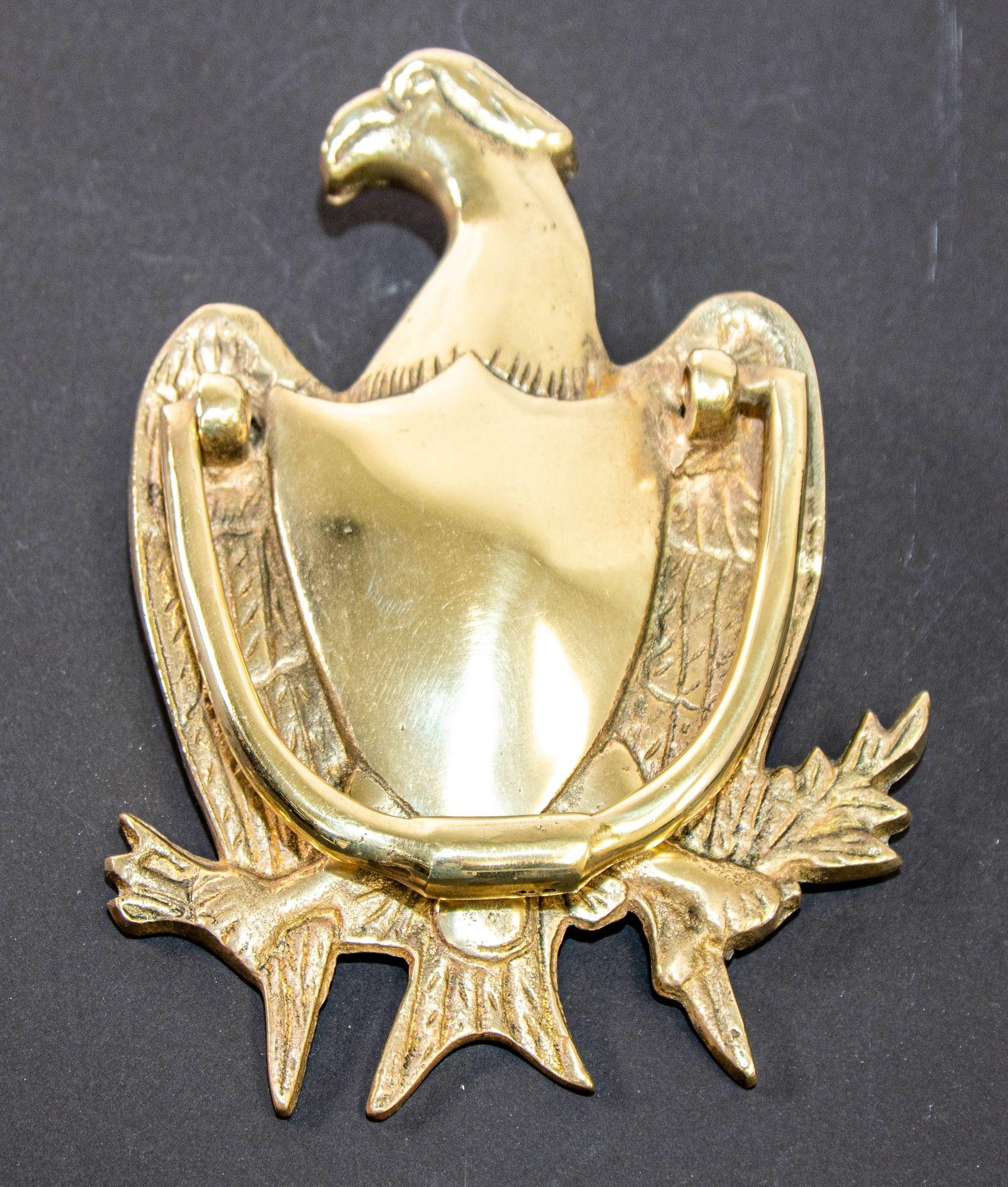 Vintage 1950s solid cast brass American Federal Eagle door knocker.
Large heavy solid cast brass American federal eagle with shield design door knocker.
Polished gold brass door knocker shaped as an American eagle with swinging handle