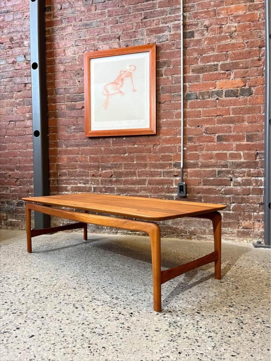 We have a rarely seen solid teak coffee table designed by Peter Hvidt for France & Daverkosen, all shined up and on display in our Chinatown showroom. This special piece is perfectly designed, with the top appearing to float on the gently curving