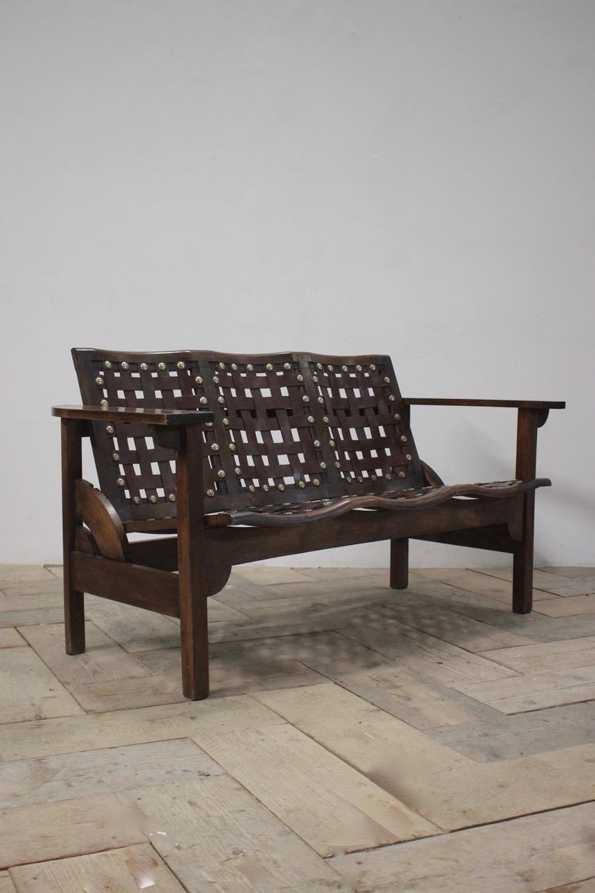 A circa 1950s Spanish folding bench in beech with lattice leather seats and decorative brass stud work decoration. Possibly Catalán. 
Measurements: 43cm High (floor to seat)