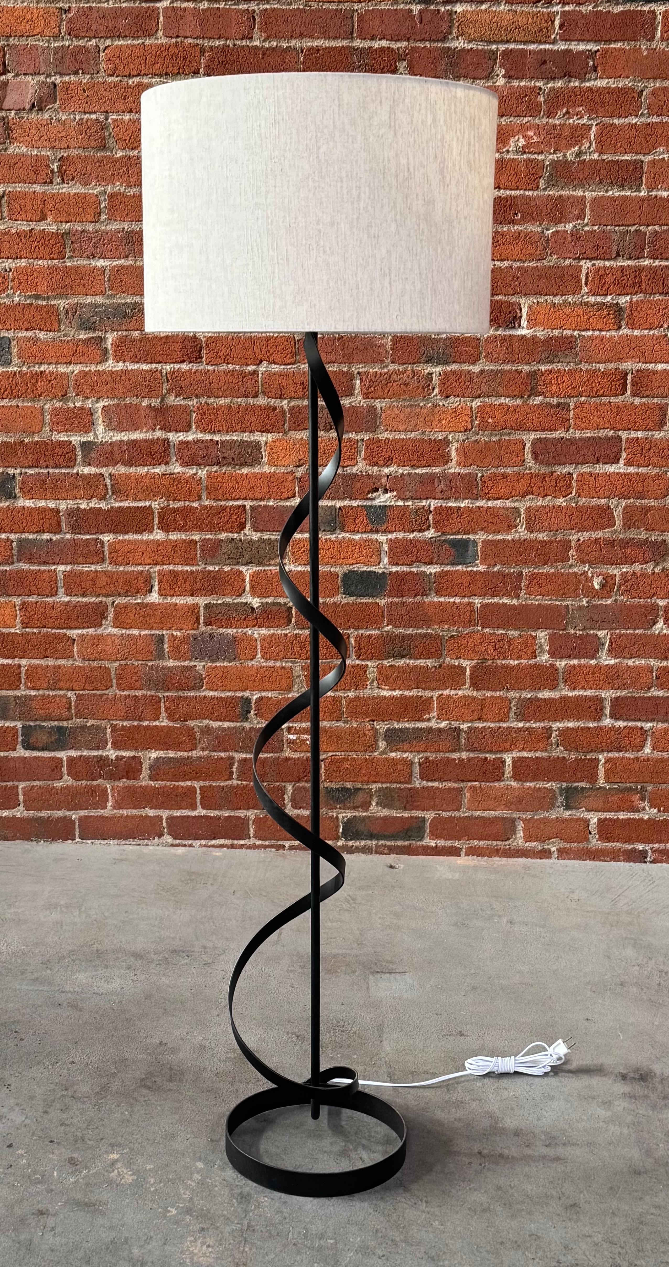 Lámpara de pie modernista de hierro en forma de espiral de los años 50 con base circular en negro, una sencilla y elegante lámpara de pie construida con tres elementos, base circular, acento en espiral y un tubo recto para el cableado. Recién