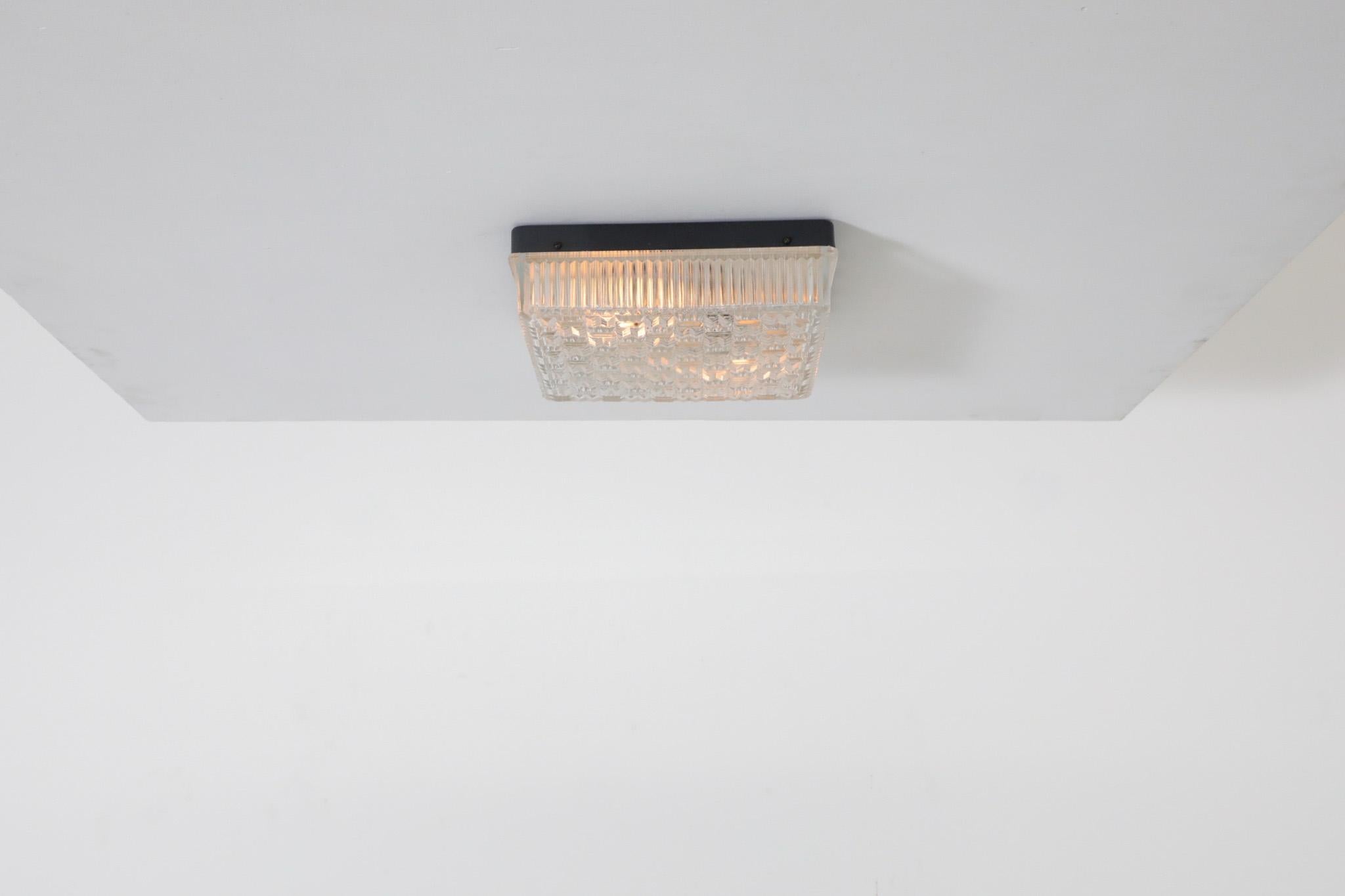 1950's square, flush mount ceiling sconce with textured pressed glass shade and black enameled metal frame. Takes two medium base light bulbs. Hardwired. In original condition with visible wear consistent with its age and use.
