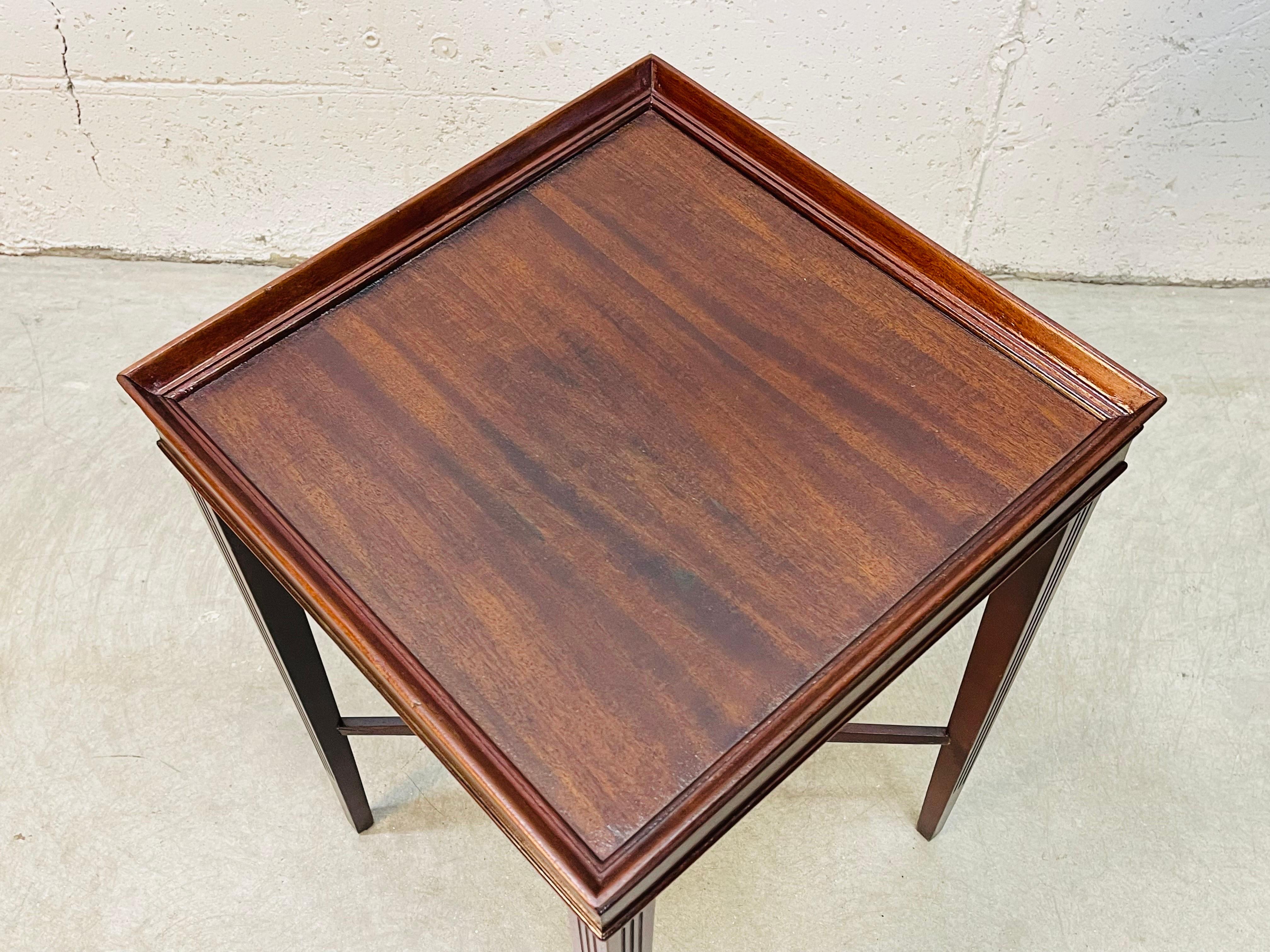 Vintage 1950s square mahogany side table with tapered legs. The legs have a triple channeled accent. The table is solid and sturdy. The table is in refinished condition. Marked underneath.