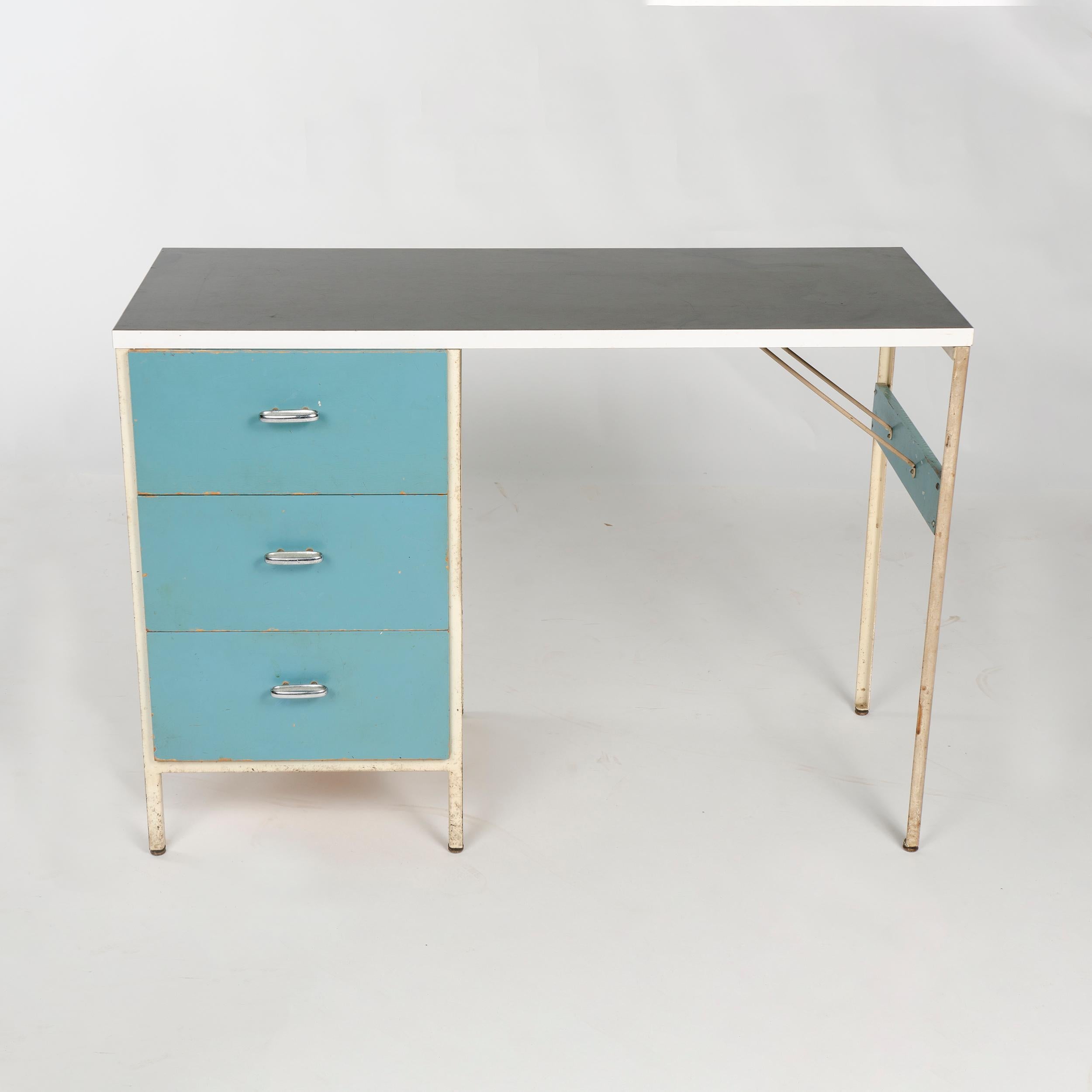 A compact white steel frame desk with three blue enameled drawers and black laminate top. 
Model 4111 from the 'Steel Frame' line for Herman Miller.