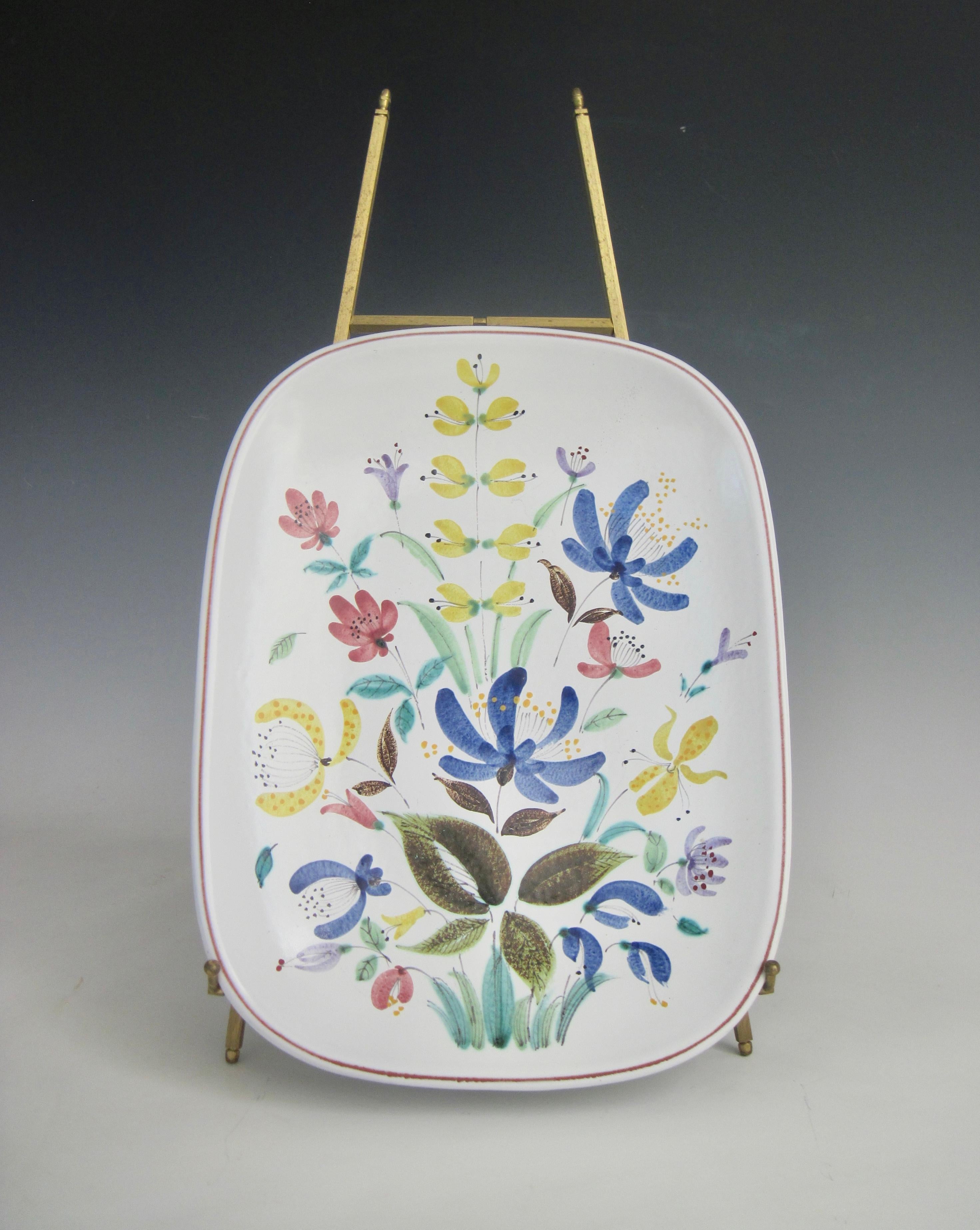 A 1950s Stig Lindberg rounded rectangular form (model 75) from the Faience series that came about, along with Gustavsberg’s artistic leader Wilhelm Kåge, starting in the 1940's. 
The sprightly painted polychrome flowers on a milky white glaze