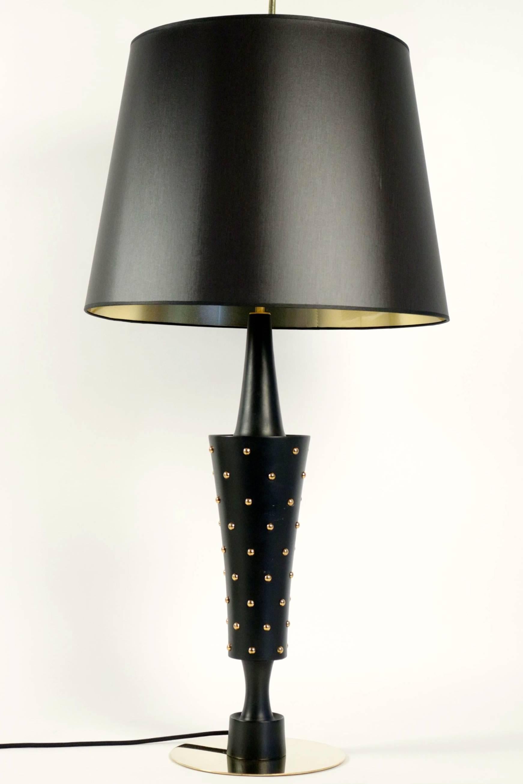 1950s Stilnovo large table lamp.

The base is made by a large brass disk. The stem of the lamp is black lacquered made of turned wood with brass nails. 
Large handmade lampshade made of black cotton with gilded inner face.
The lamp is toped with