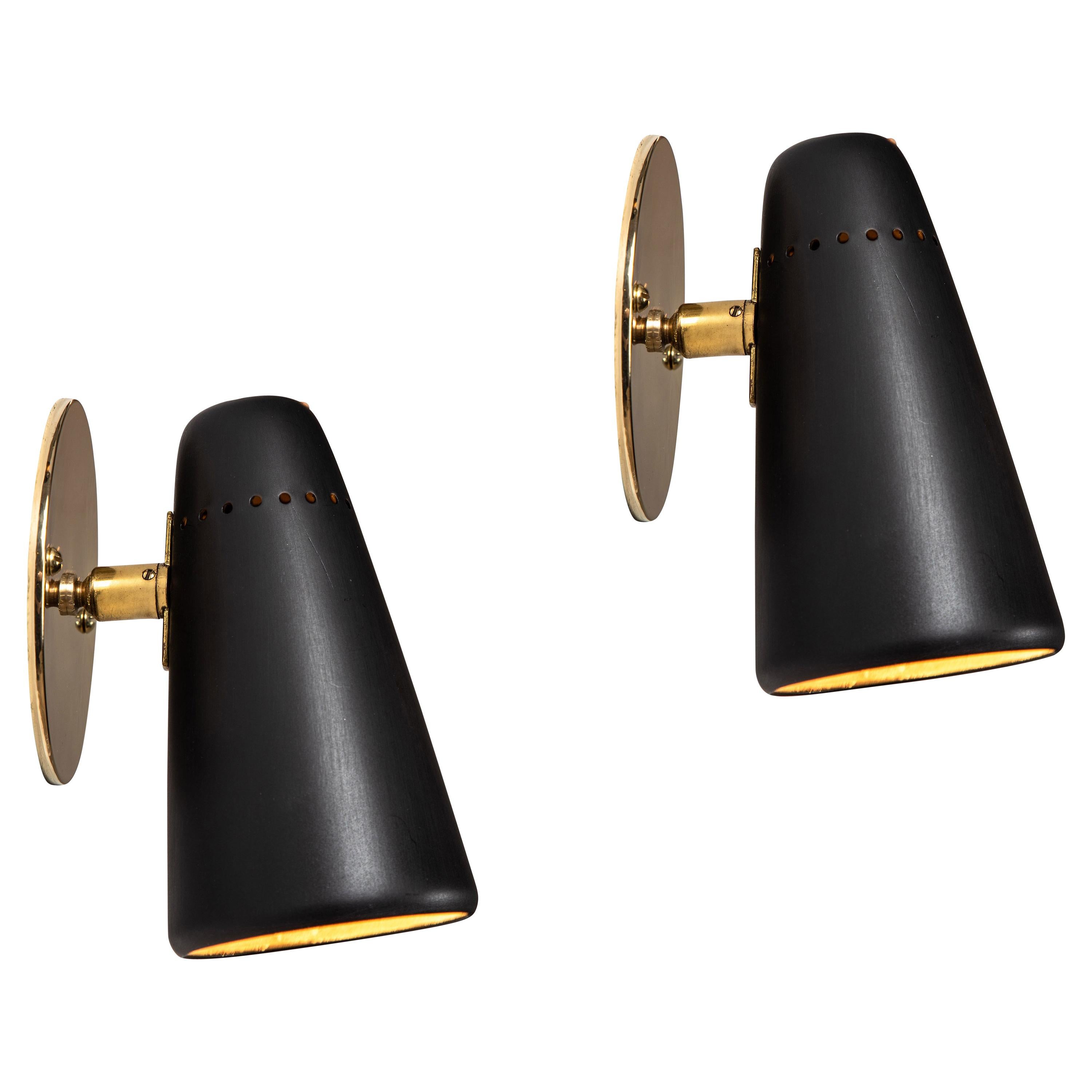 1950s Stilnovo adjustable sconces in black and brass. A quintessentially 1950s Italian design executed in black painted metal with custom brass backplates for mounting over a standard American juncture box. Shades can be rotated freely on a brass