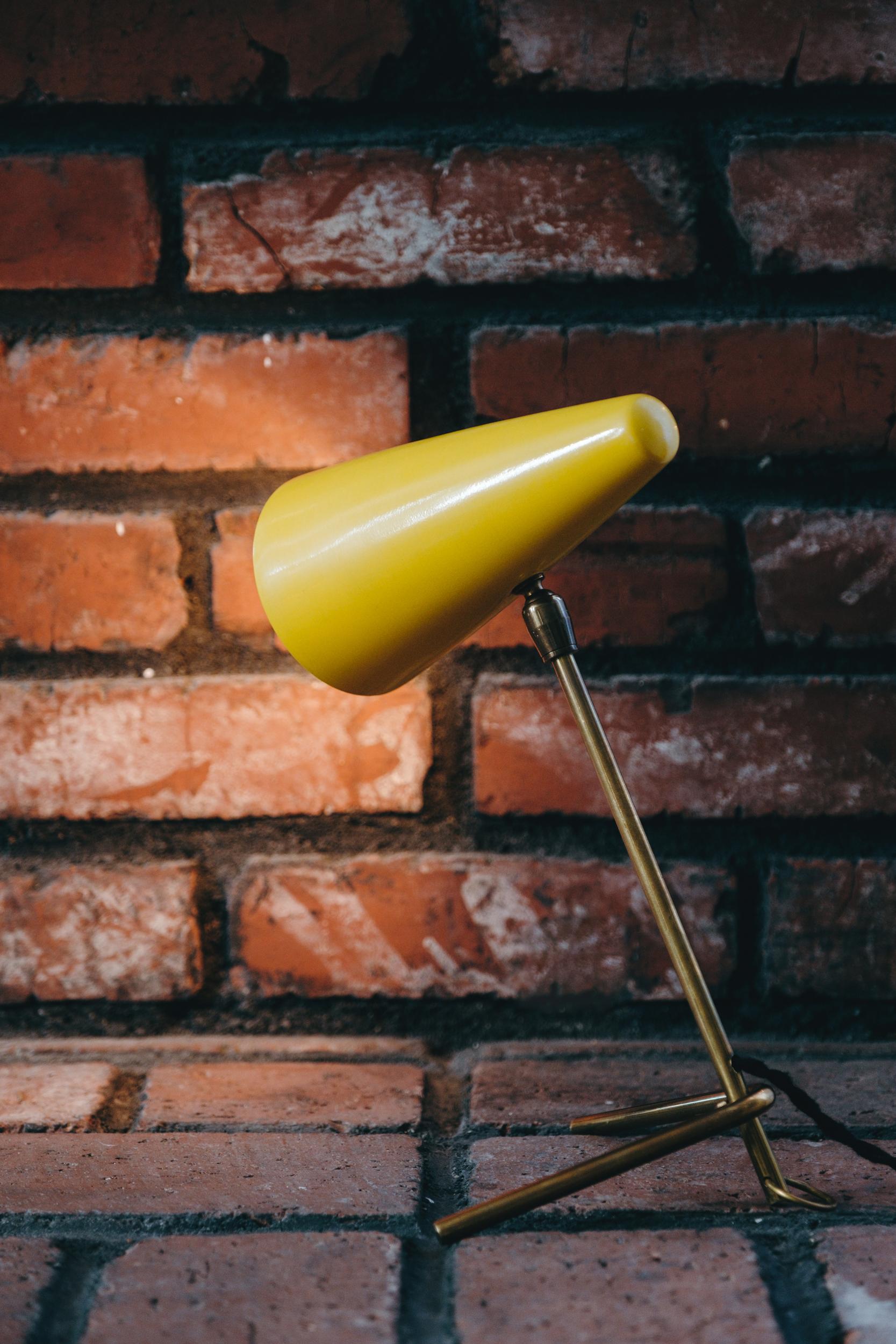 1950s Stilux Milano yellow conical table lamp. This quintessentially midcentury Italian table lamp is executed in a conical yellow painted metal shade mounted on a patinated brass arm and V-shaped legs in very good vintage condition.

Stilux was