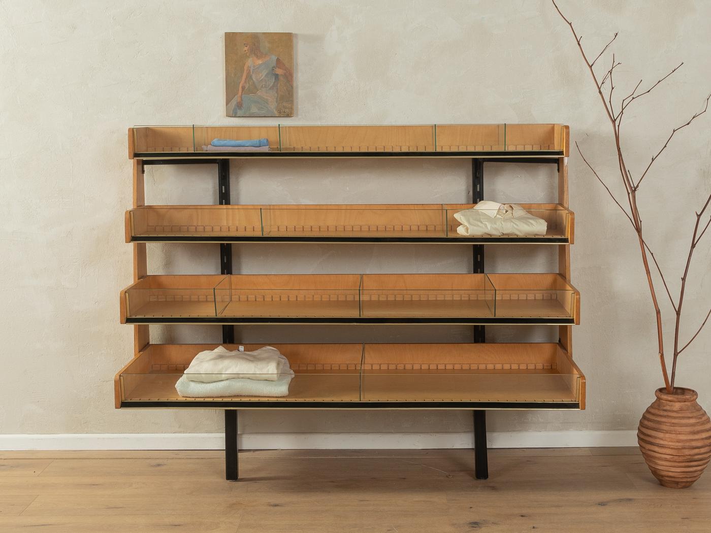 Wonderful store shelf from the 1950s. Corpus in oak veneer with 14 shelves, 10 glass dividers and a black metal frame.

Quality Features:
very good workmanship
high-quality materials
Made in Germany, manufacturer: Perter Ruppel (Branding on the