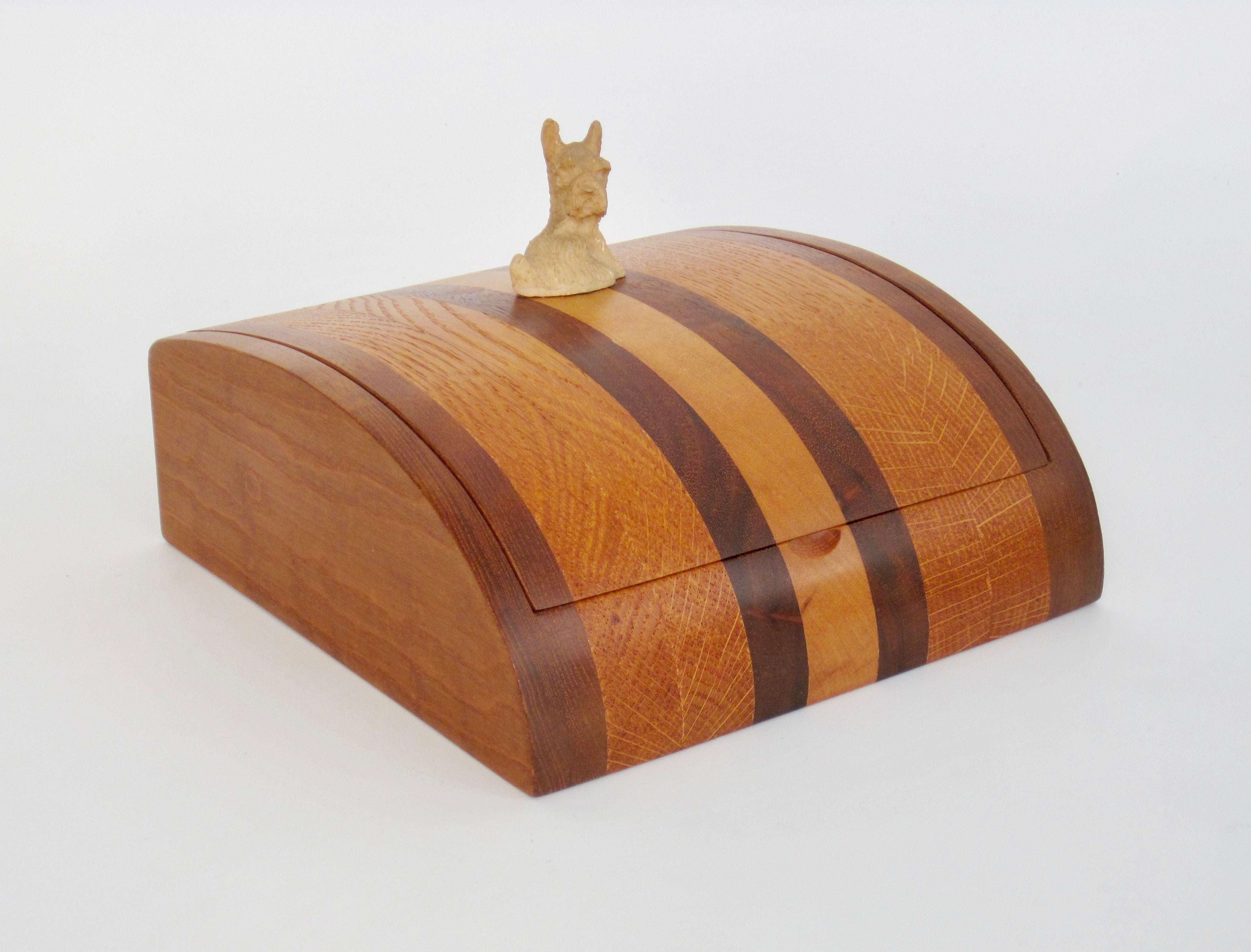 A finely constructed, studio made, banded walnut and maple dowel hinge box. The wood hinges allow the top to open effortlessly. The polished exterior and curved top really show off woodgrain nicely.  We love how the scottie dog is a nod the Art Deco