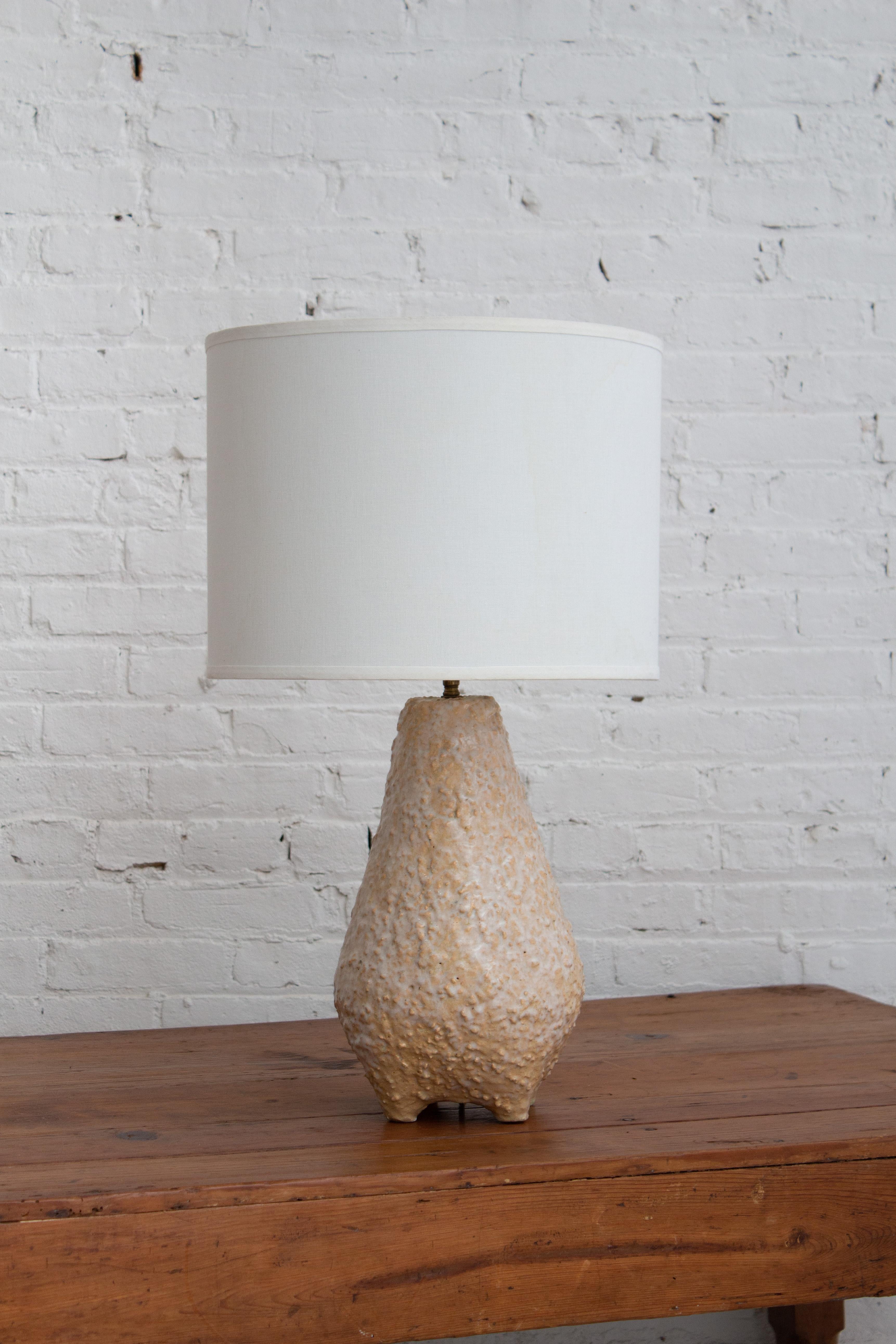 A mid century studio made ceramic lamp. Organic silhouette with a textured surface and glossy glaze. Ceramic measures 15” to base of hardware. Lampshade not included.