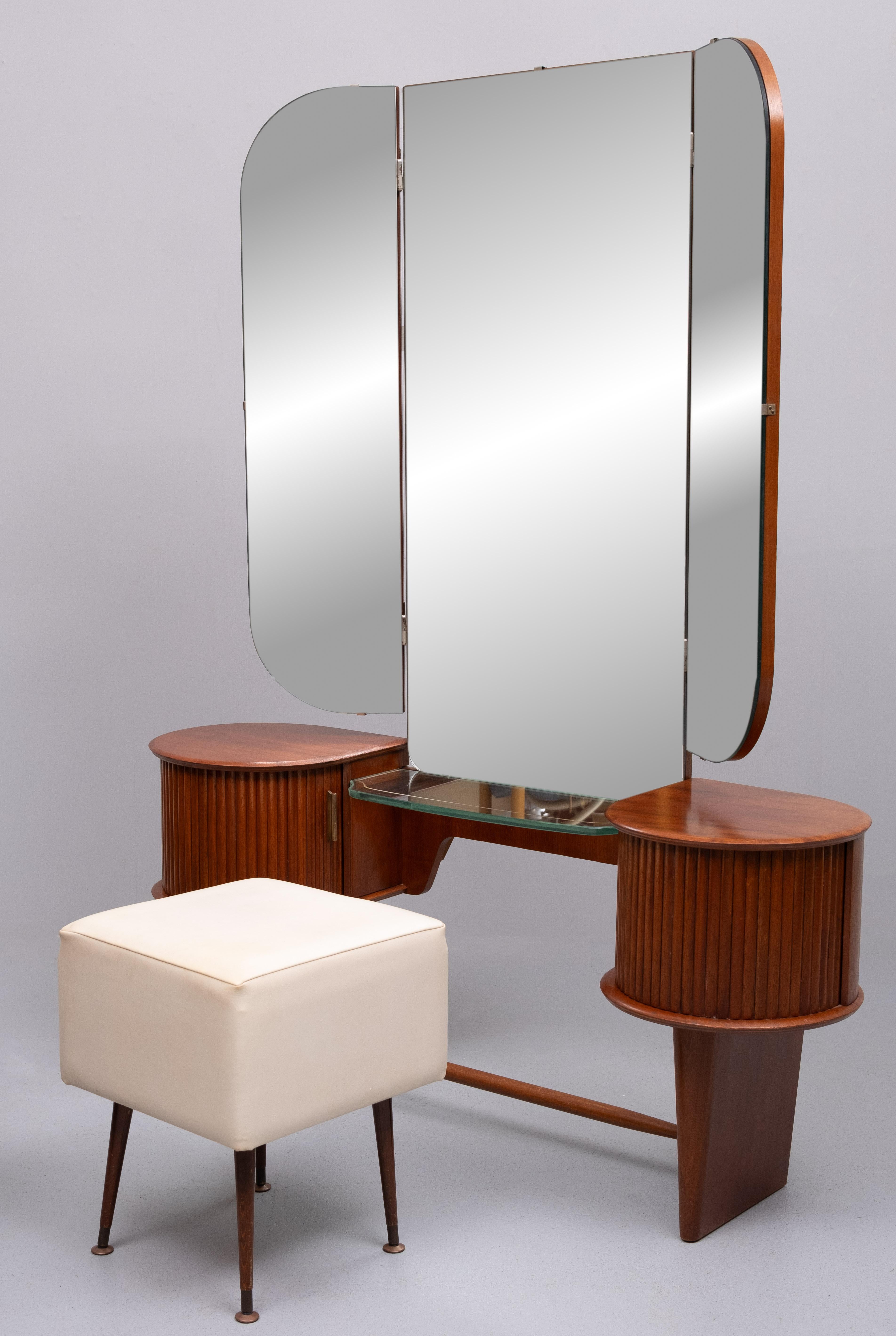 Love this dressing table . Round shaped cabinets with tambour 
doors ,comes with solid Brass handles . Between the  cabinets a thick 
curved Glass plate ,decorated with a Gold lining ,inside a revolving Tray
And on top folding mirrors , comes with a