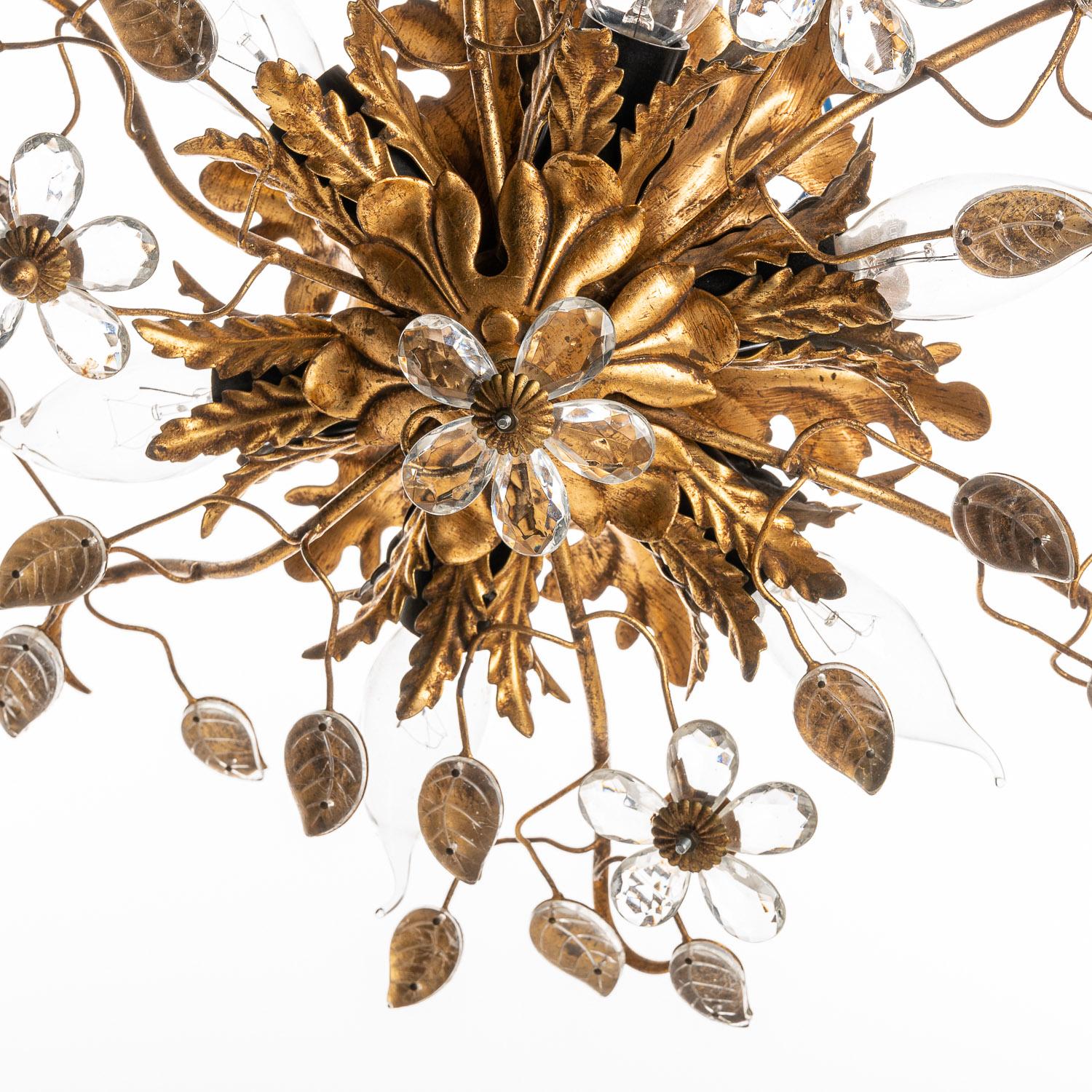 This intricately-crafted piece comes from the 1970s designer Bani Firenzi. The brass-coloured arms stretch and weave together from the base, branching out to beautifully ornate leaves and crystal flowers. The base contains six connections for bulbs,