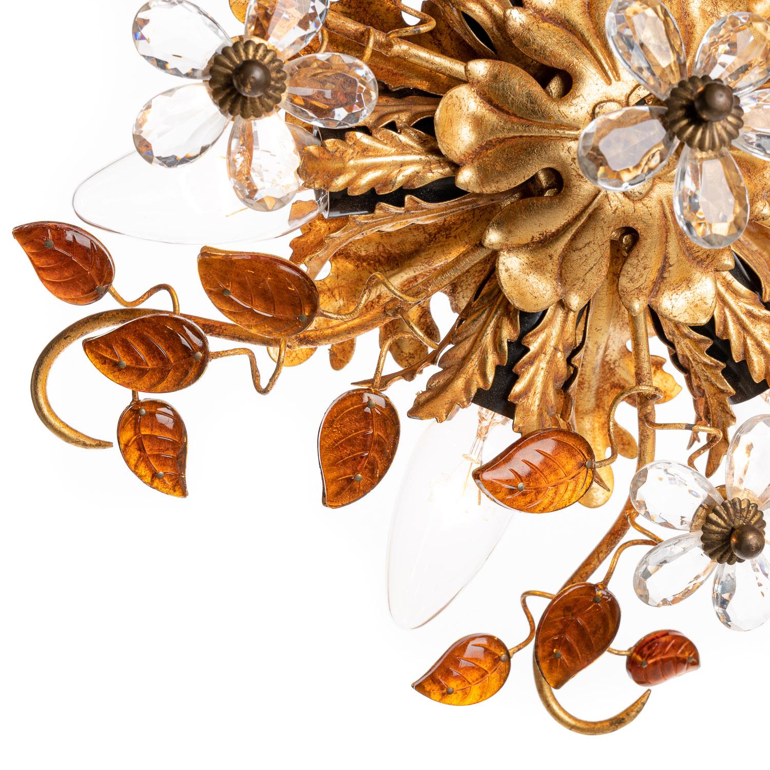 This intricately-crafted piece comes from the 1970s designer Bani Firenze. The brass-colored arms stretch and weave together from the base, branching out to beautifully ornate amber glass leaves and crystal glass flowers. The base contains six