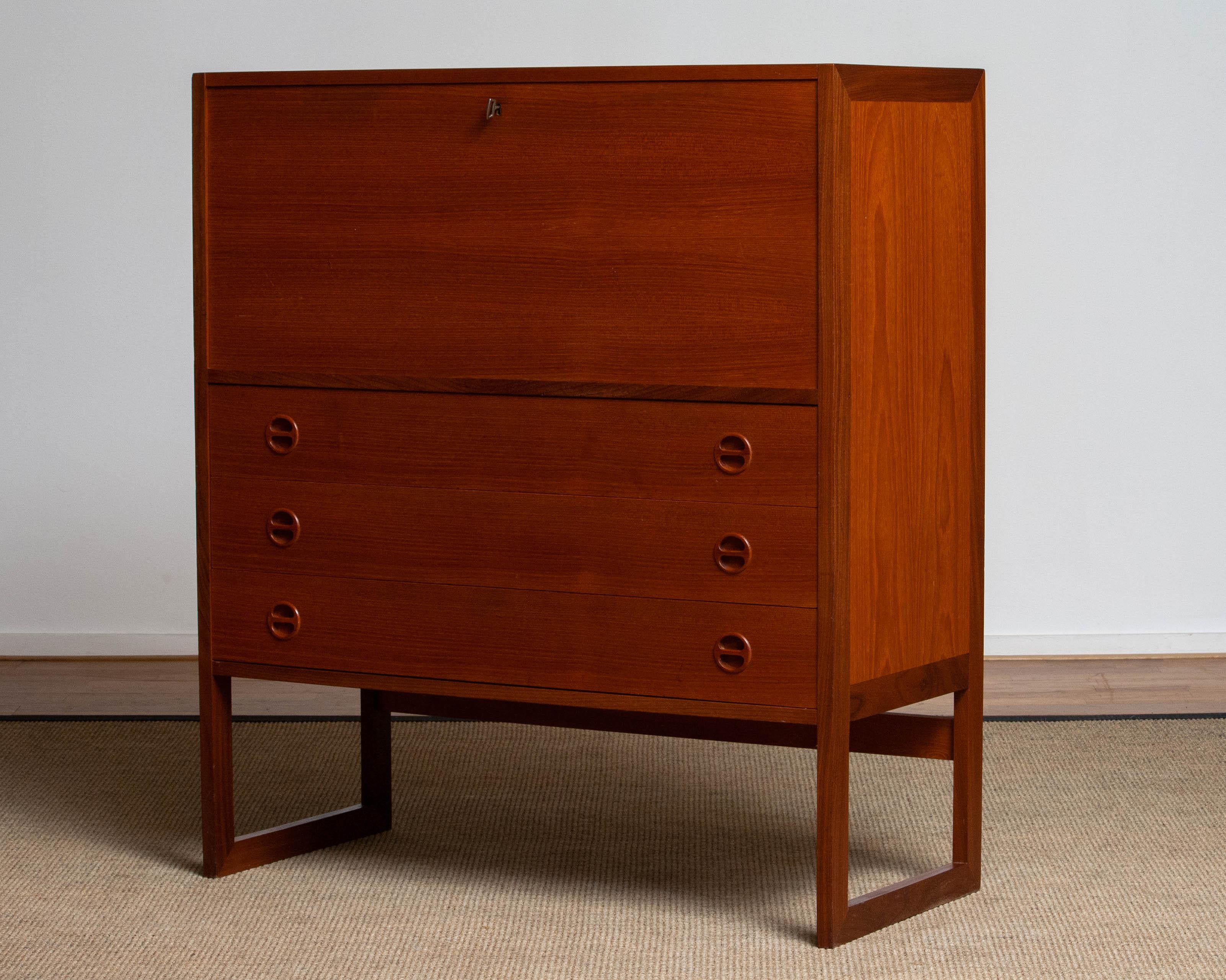 Beautiful secretaire, also perfectly used as a vanity or desk in teak designed by Arne Wahl Iversen from Sweden.
Consisting three drawers at the front and a folding writing desk. Inside this storage piece is build up in beech accept the three oak