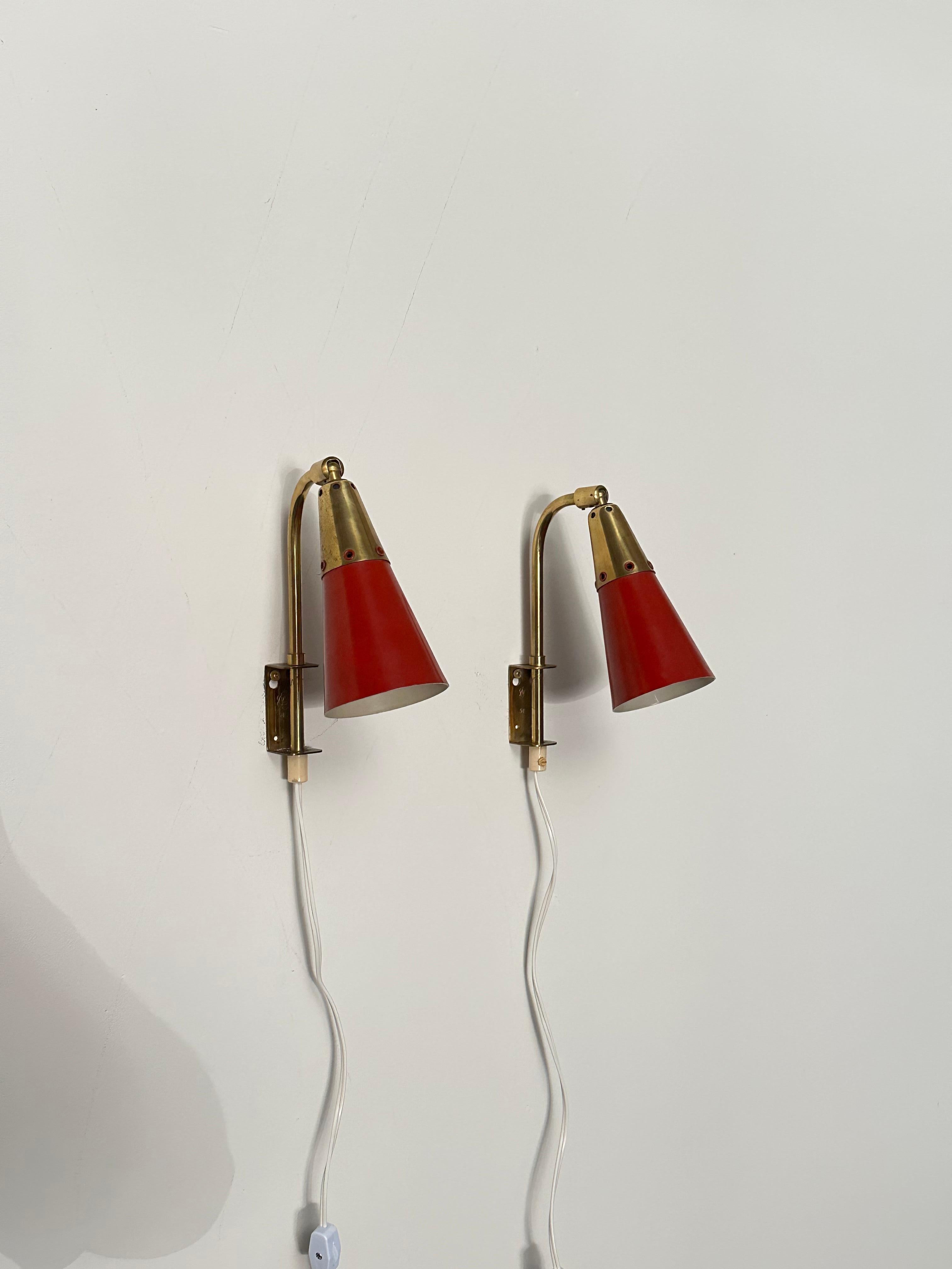 Coppia di applique prodotte in Svezia negli anni '50 circa. Presenta un paralume a cono di colore rosso con fori forati vicino all'estremità più stretta. Il paralume è orientabile verso l'alto e verso il basso e può essere spostato da un lato