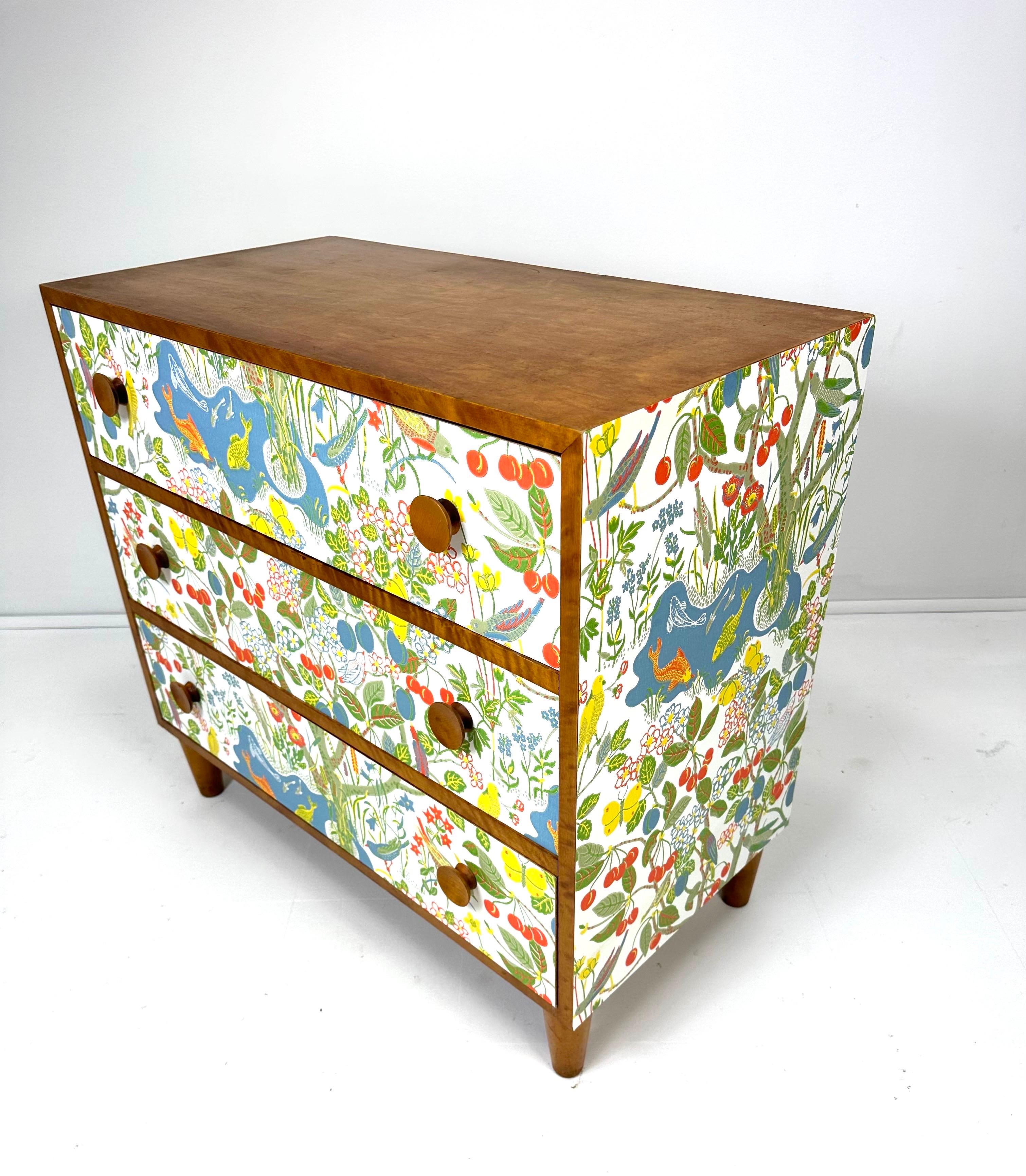 1950’s Swedish three drawer dresser. Dresser later papered in “Paradiset” designed by Josef Frank. Paper originally designed around 1947 contains a constellation of flowers, fruits, trees, butterflies, birds and fish. Cabinet made of Birch wood.