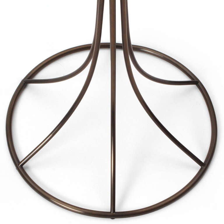 A unique floor lamp with a tulip shade on an open frame tubular brass base that retains its original cream silk covering.