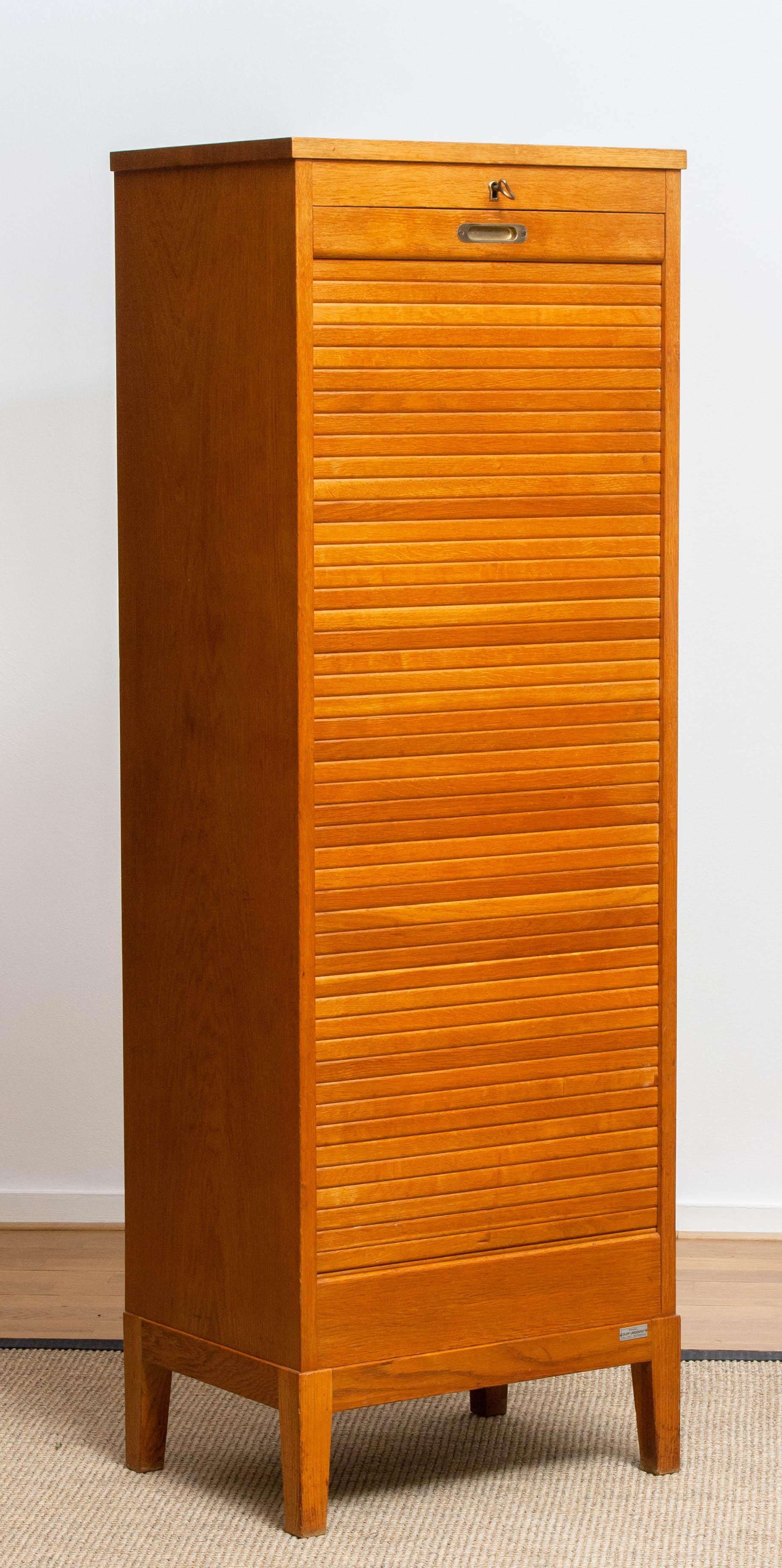 Beautiful upright and narrow oak archive / files cabinet with twelfths drawers behind the perfect sliding tambour door designed and built by Olof Lundqvist Götenburg Sweden.
The Internal spring that helps the door coming up is also in great