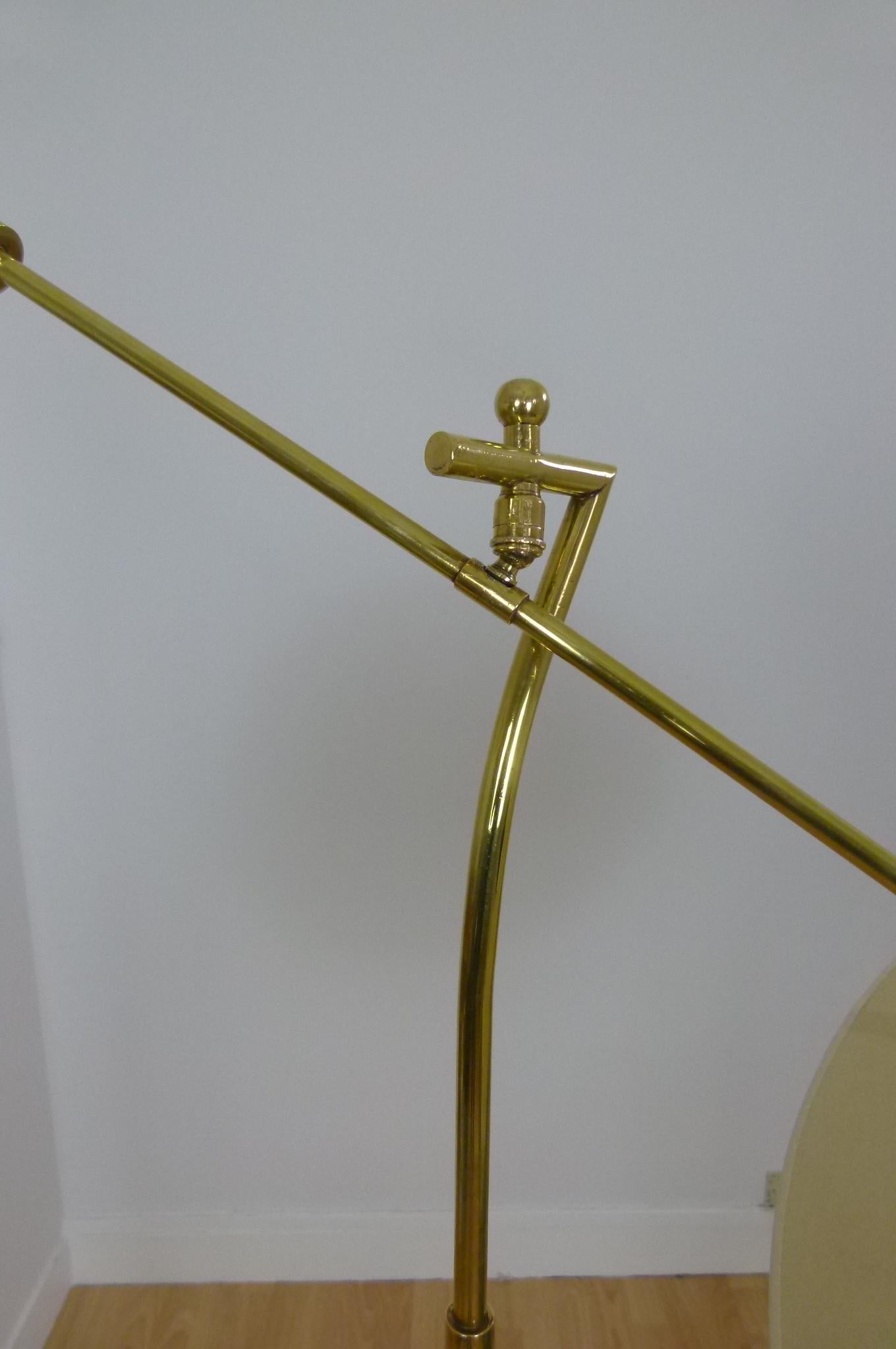 Floor lamp in brass and black lacquered metal composed of a solid brass tripod on which is placed a flared teak wood rod carrying a brass wall lamp with a counterweight end.
The illuminated arm is articulated with a brass ball.
The slightly flared