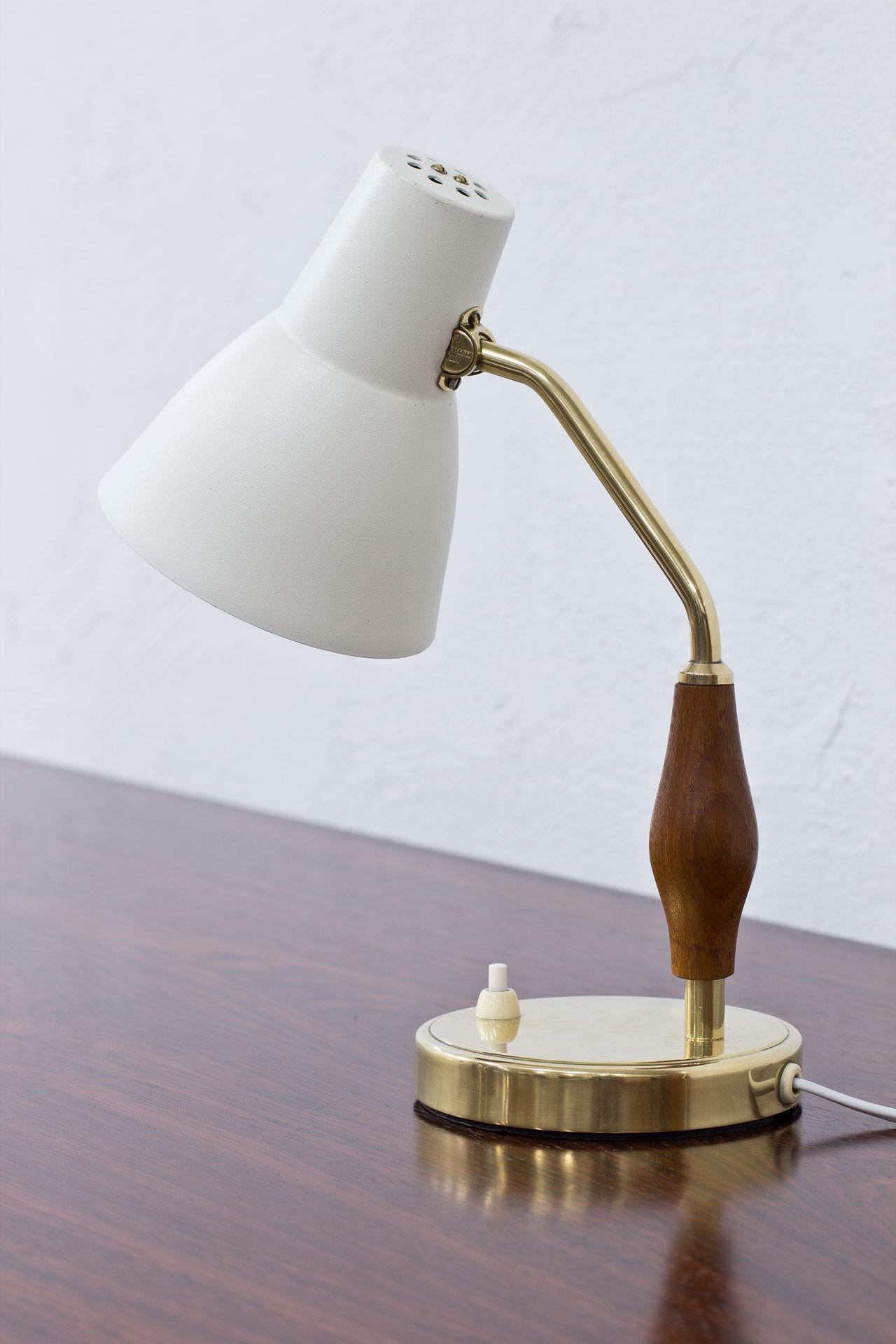 Neat desk/ table lamp designed by Hans Bergström, manufactured by ASEA in Sweden during the 1950s.
Off-white lacquered metal shade, brass base and sculpted teak handle. 
Rewired.
