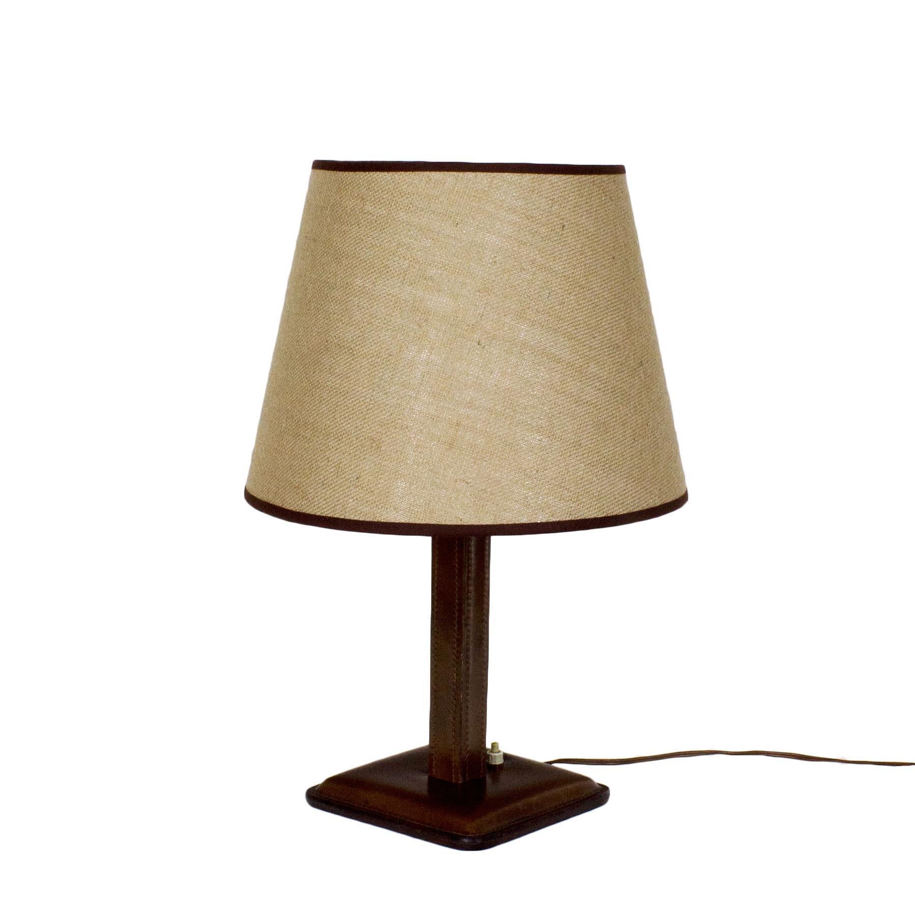 Table lamp, wood covered with leather, light thread sewing, jute lampshade with a brown fabric edging.

Spain, circa 1950.