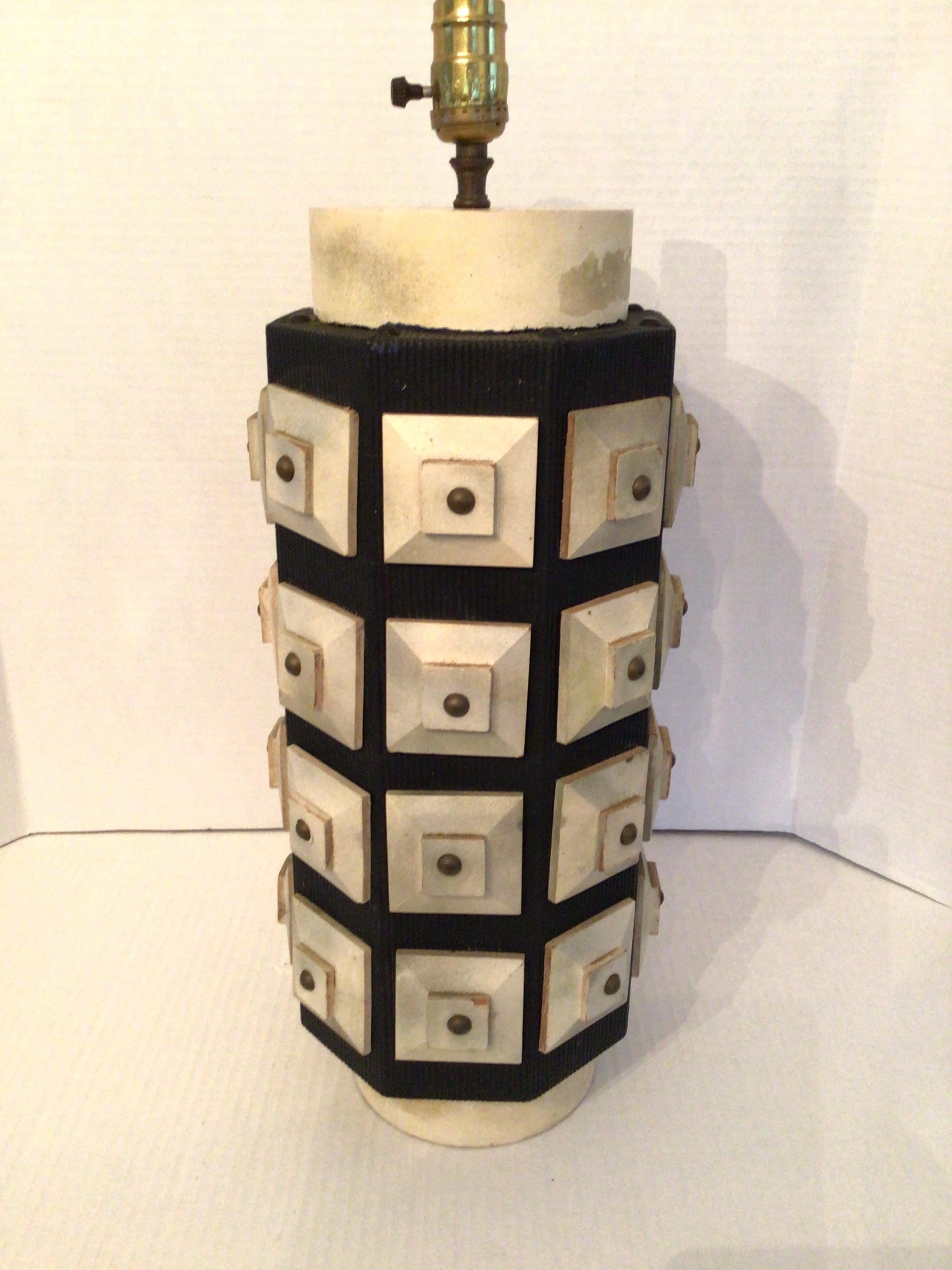 Lampe de table des années 1950 à motif géométrique en relief
Cette lampe se compose d'un corps en bois massif recouvert de vinyle noir avec un motif de grille en bois recouvert de blocs carrés en relief de couleur plus claire, chacun doté d'un