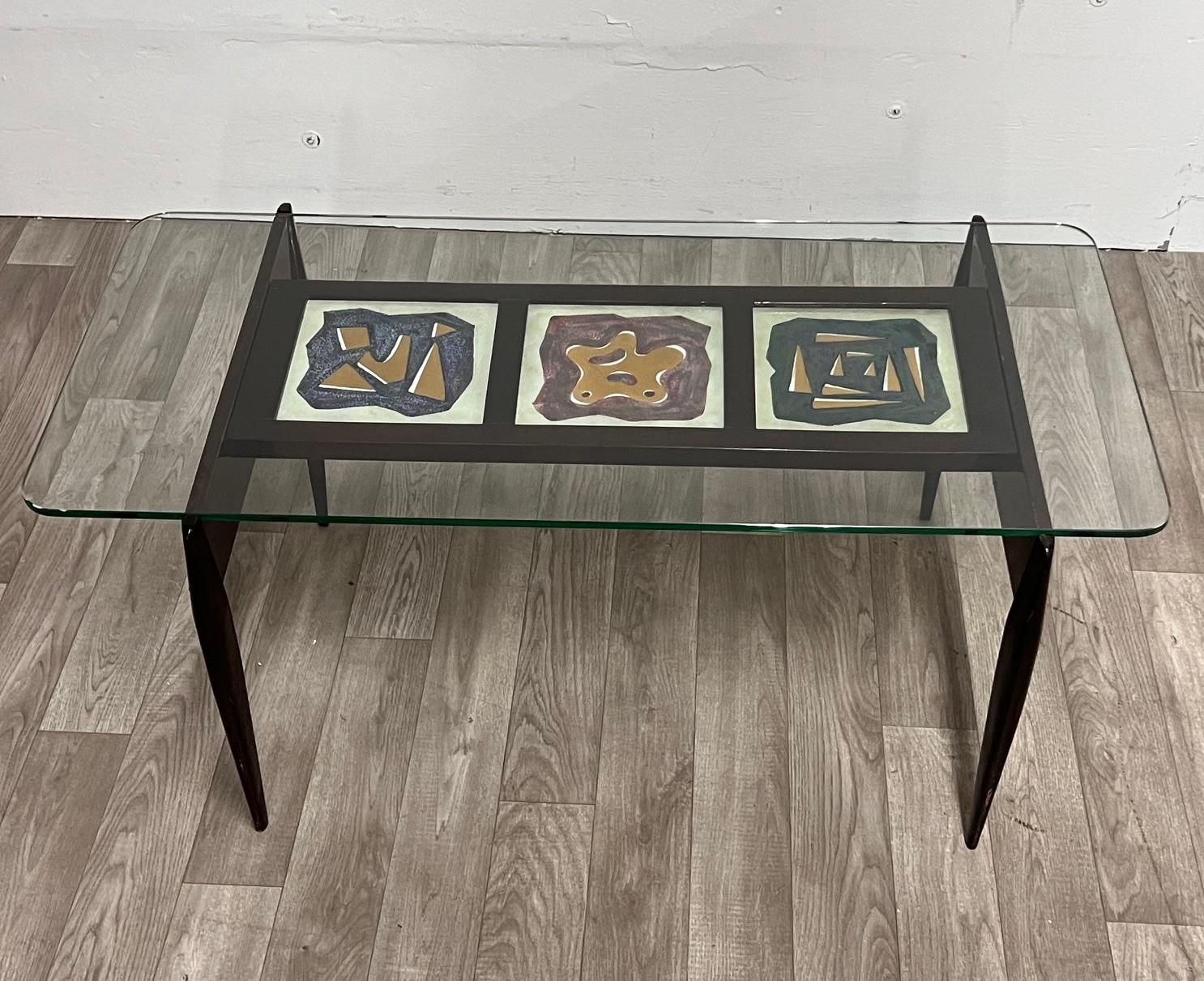 Cette élégante table vintage des années 1950 est fabriquée en bois teinté. Le plateau en verre repose sur un panneau décoratif avec des carreaux de céramique émaillée brillante.
Besoin d'une restauration mineure 