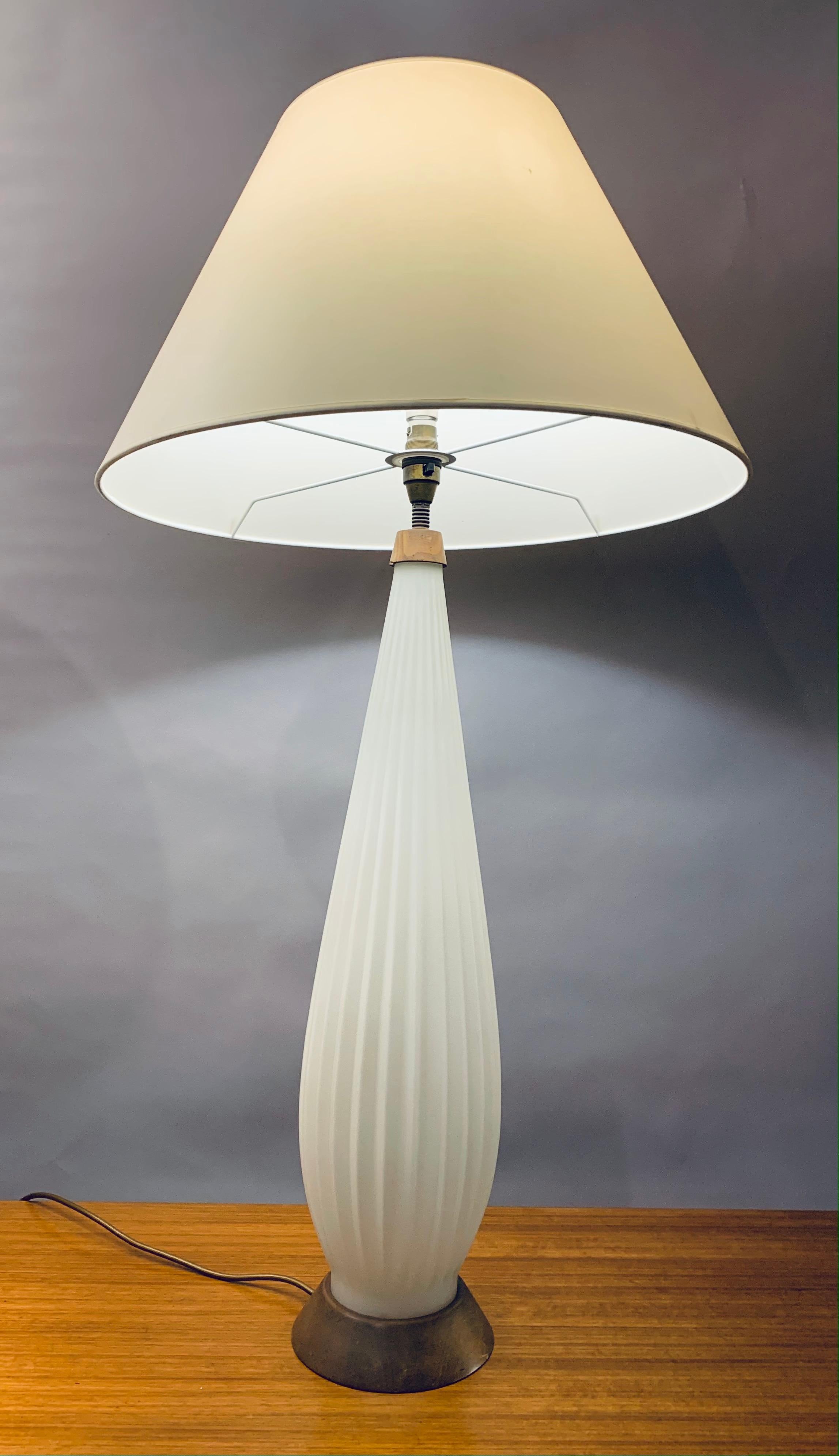 1950s, Italian, Alfredo Barbini style, tall, opaque-white, ribbed, Murano glass elegant table lamp. A beautiful and majestic lamp with a tapered wooden base which matches the top where the bayonet bulb light socket sits. A 