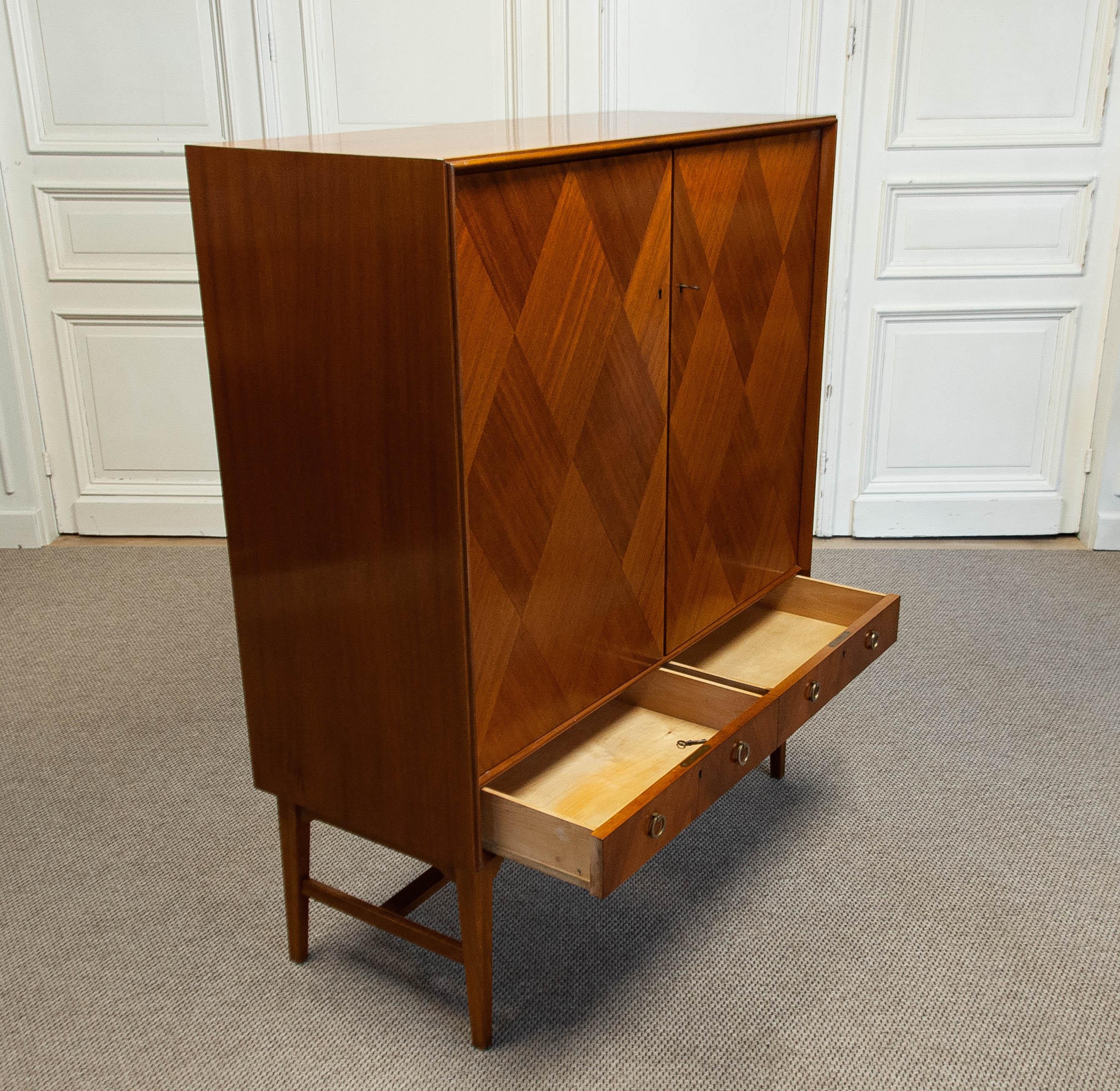 A beautifully crafted mid-century tallboy dresser designed by Holmström Johansson in Sweden, featuring a refined Scandinavian aesthetic.

Material: Teak veneer with a striking spear-woven pattern
Storage: Five drawers made of beech wood and three