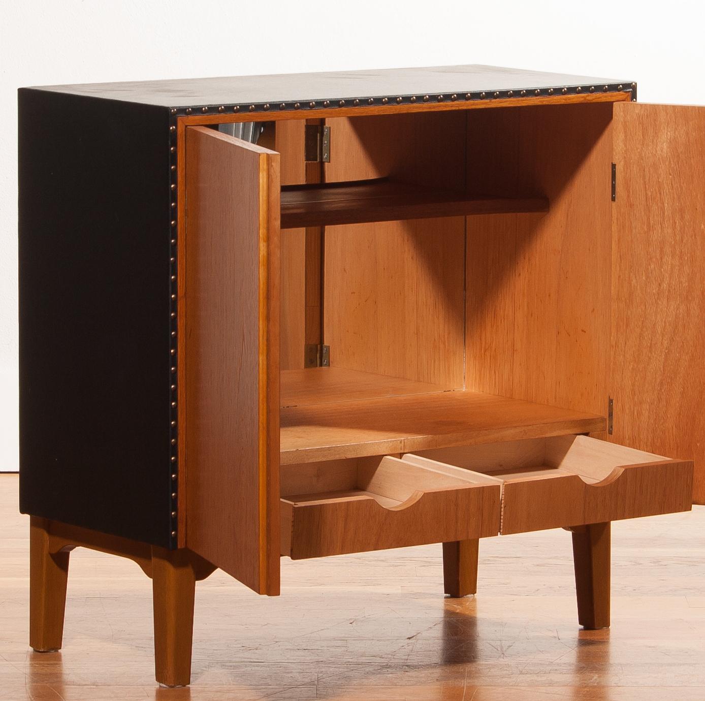 Beautiful mini-bar in teak and covered with black leatherette designed by Bertil Fridhagen for Bodafors.
The mini bar is complete with the original mirror-back, hollow shaped shelf for the glasses and two drawers.
All in perfect condition.
A