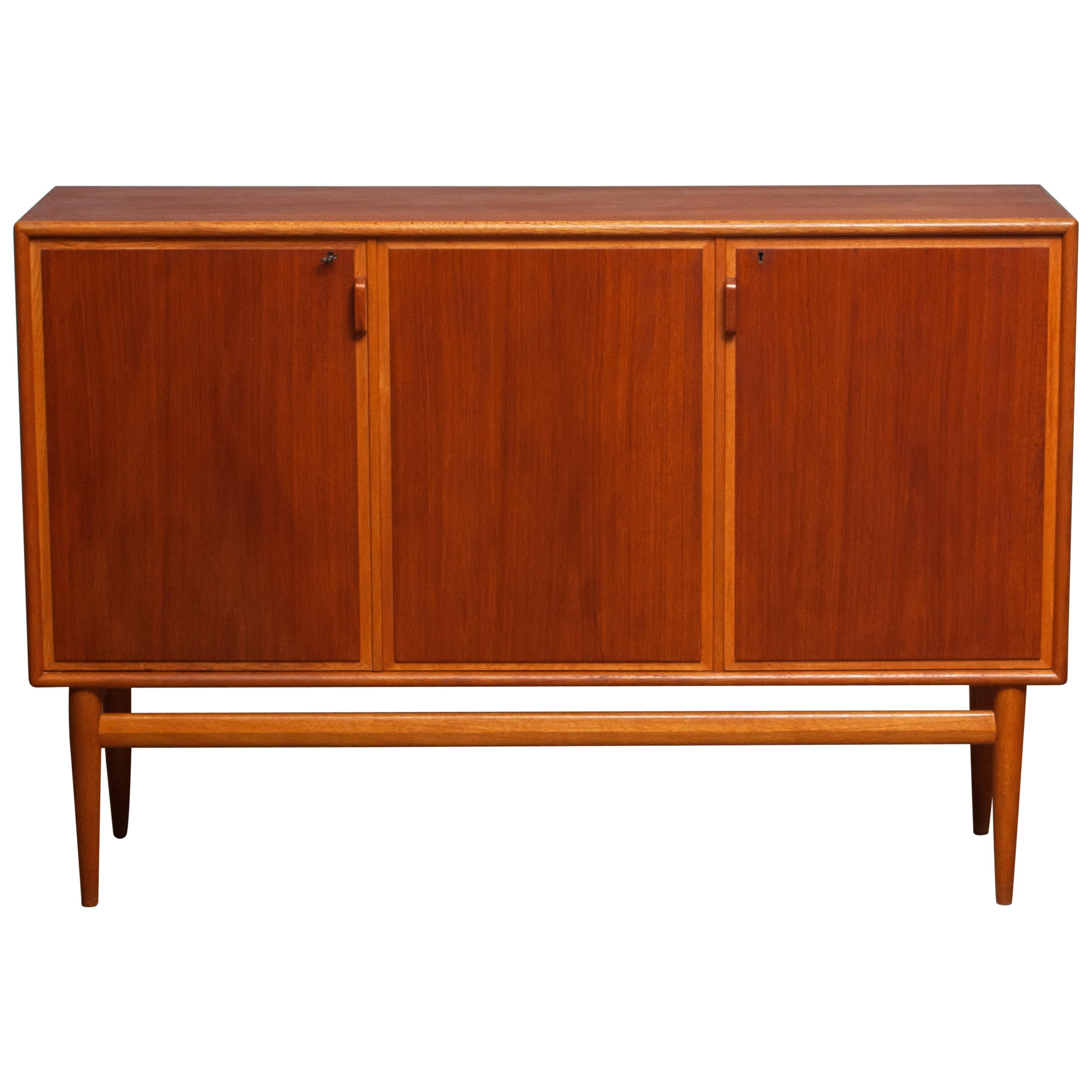 Beautiful and high quality credenzas / buffet cabinet designed by Bertil Fridhagen for Bodafors, Sweden.
The cabinet is made of teak with oak details, the high and stately legs are also in solid oak.
The front consists three swing doors. Once open
