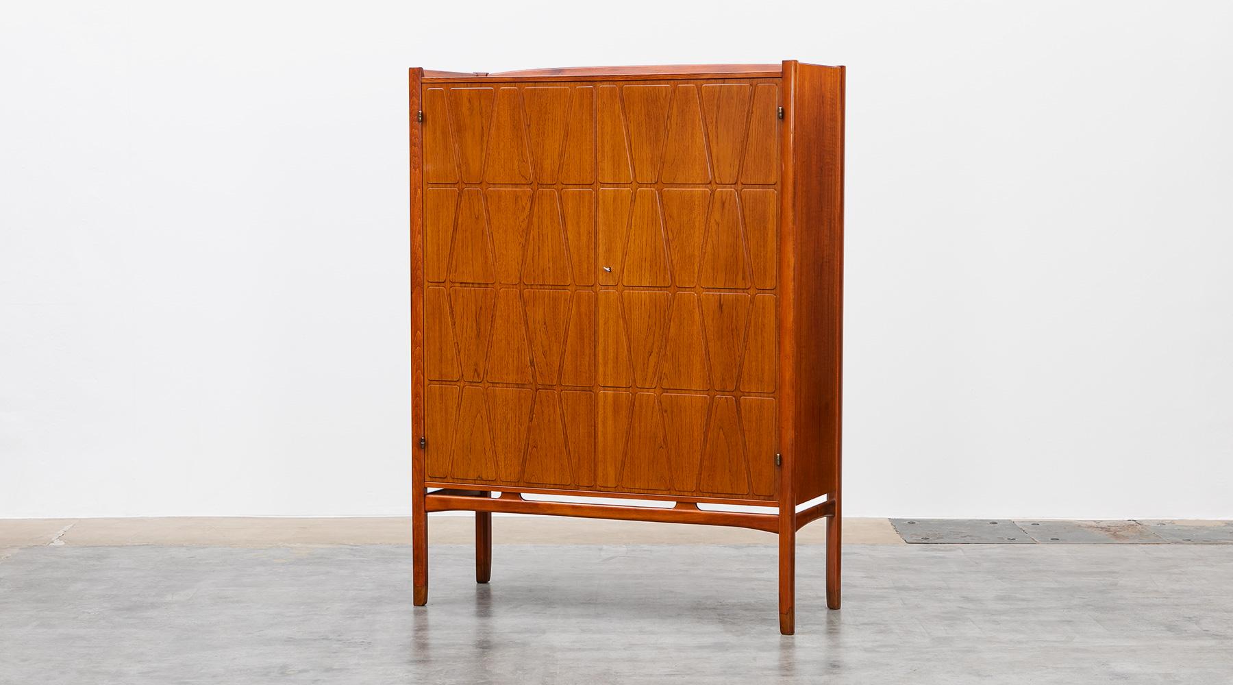 Highboard, teak and oak frame, Yngve Ekström, Sweden, 1950.

The cabinet in teak is designed by Yngve Ekström. Two beautiful teak doors with milled relief decor, interior with pullout trays and shelves. Teak-capped legs and oak