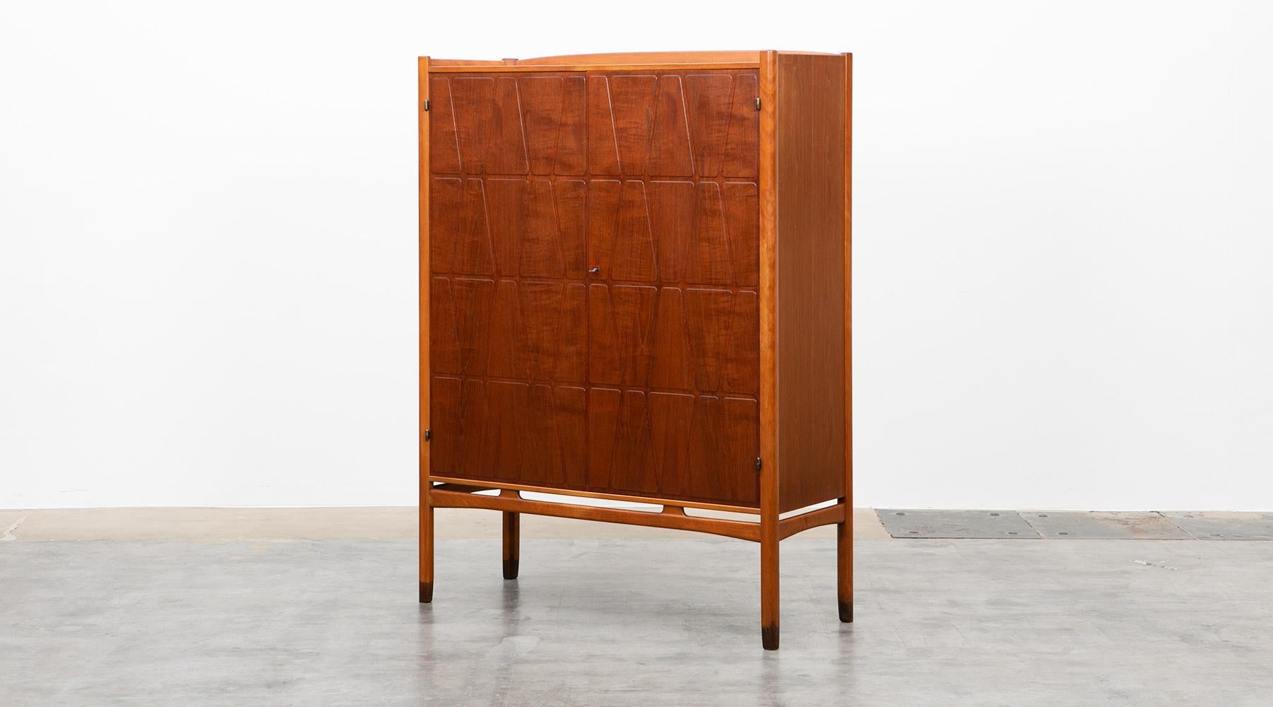 Highboard, teak and oak frame, Yngve Ekström, Sweden, 1950.

The cabinet in teak is designed by Yngve Ekström. Two beautiful teak doors with milled relief decor, interior with pullout trays and shelves. Teak-capped legs and oak