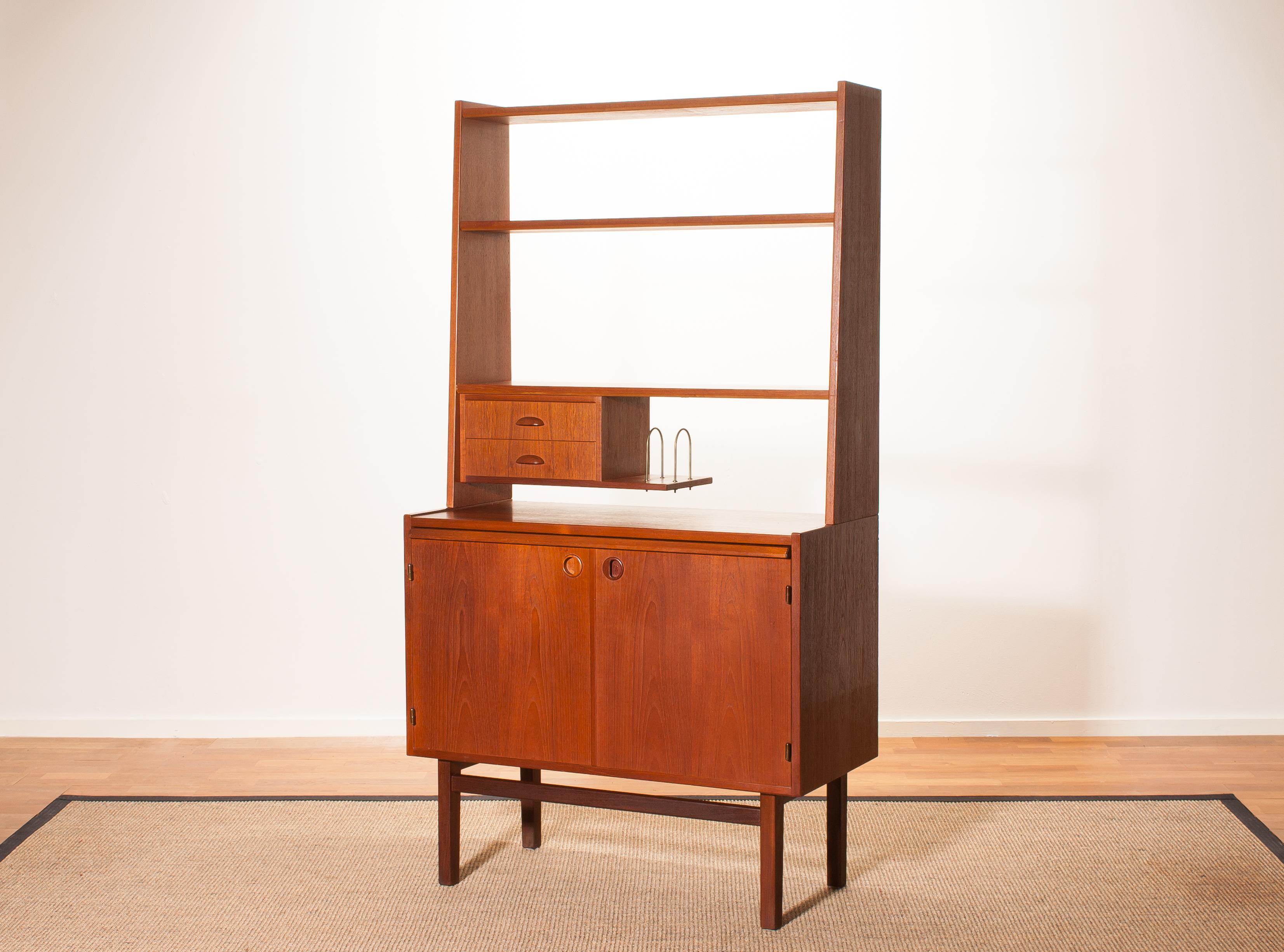 Beautiful secretaire made by Hovmantorp, Sweden.
This cabinet is made of teak and is in a very nice condition.
It has an extensible writing space and a brass letter stand.
Period 1950s.
Dimensions: H 157 cm, W 85 cm, D 41 cm (D 68 cm with the