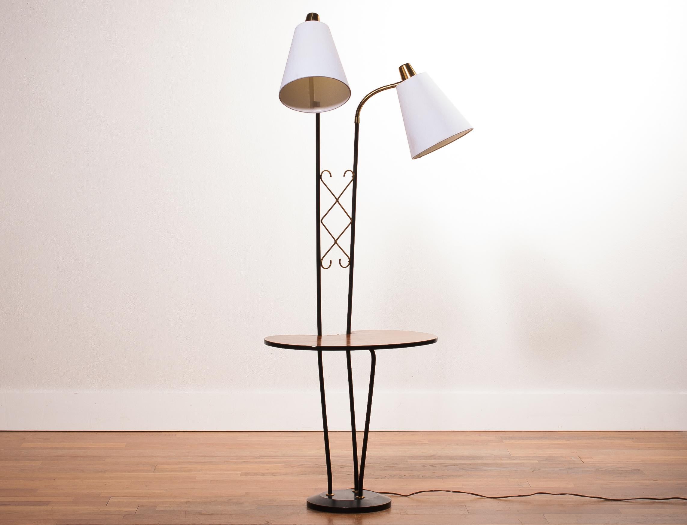 Beautiful floor lamp consistent two lamps and a table made in Sweden.
The lamp is made of a metal black with brass frame, a teak table and two lamps with new white shades.
It is in wonderful condition.
Period 1950s.
Dimensions: H 150 cm, W 54