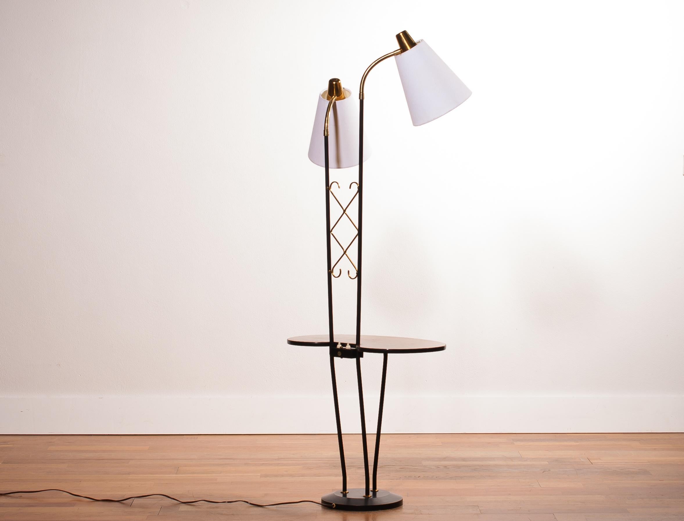 Beautiful floor lamp consistent two lamps and a table made in Sweden.
The lamp is made of a metal black with brass frame, a teak table and two lamps with new white shades.
It is in wonderful condition.
Period, 1950s.
Dimensions: H 150 cm, W 54