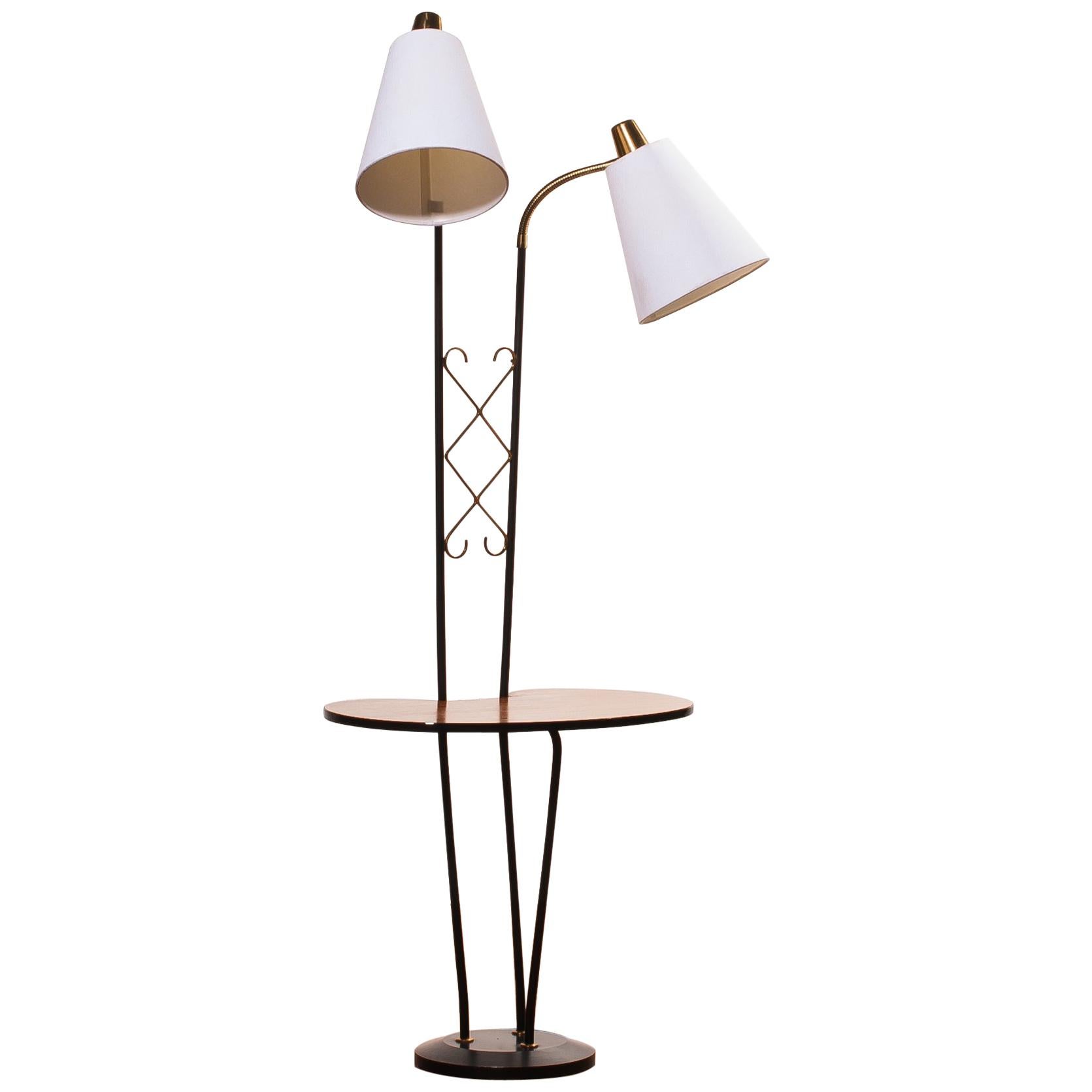 Beautiful floor lamp consistent two lamps and a table made in Sweden.
The lamp is made of a metal black with brass frame, a teak table and two lamps with new white shades.
It is in wonderful condition.
Period 1950s.
Dimensions: H 150 cm, W 54