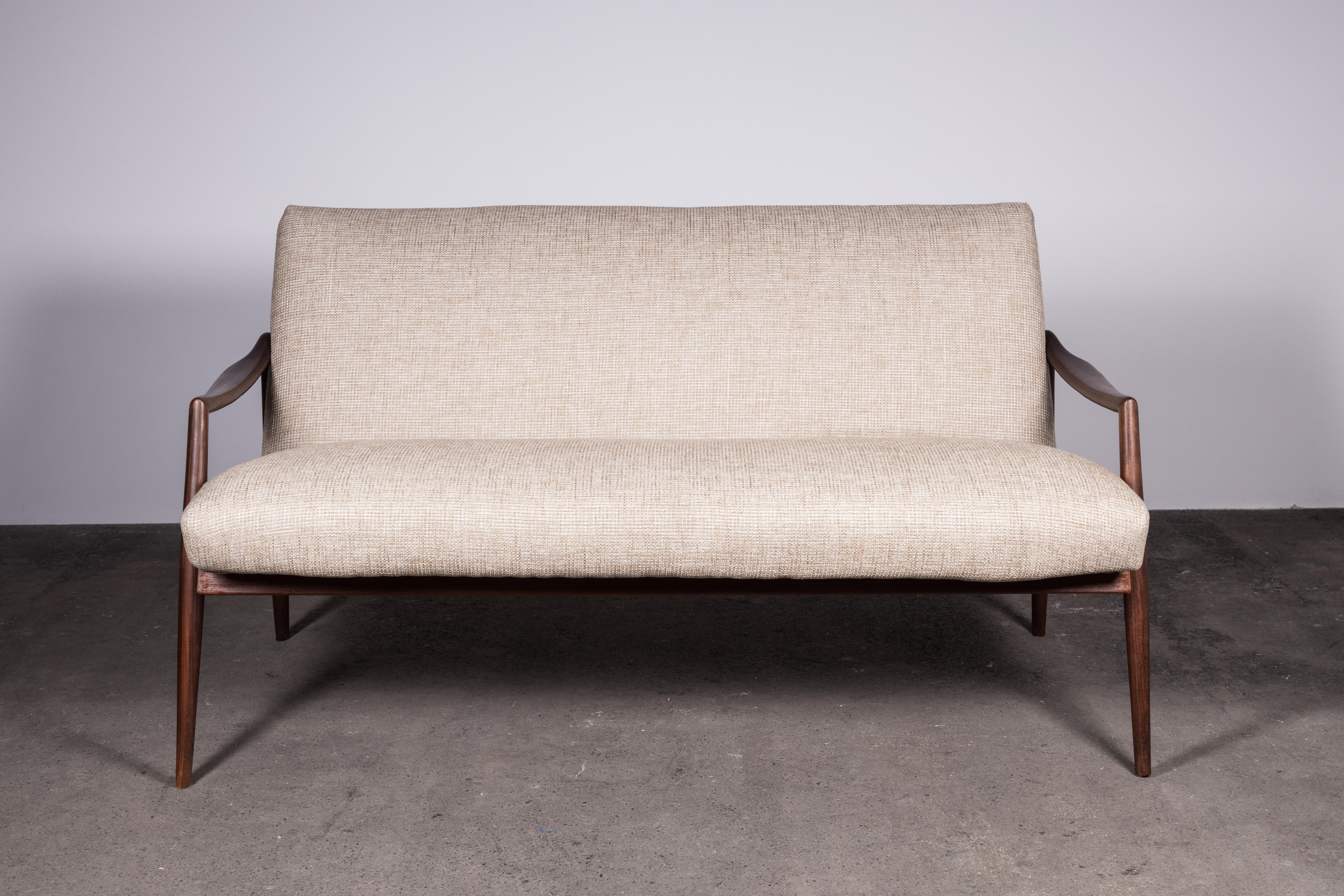 The epitome of Mid-Century Modern refinement. This iconic teak loveseat sofa represents some of the best design and craftsmanship of the era.

Invitingly relaxed and magnificently elegant.

The sculpted teak wood, elegantly darkened with age, is