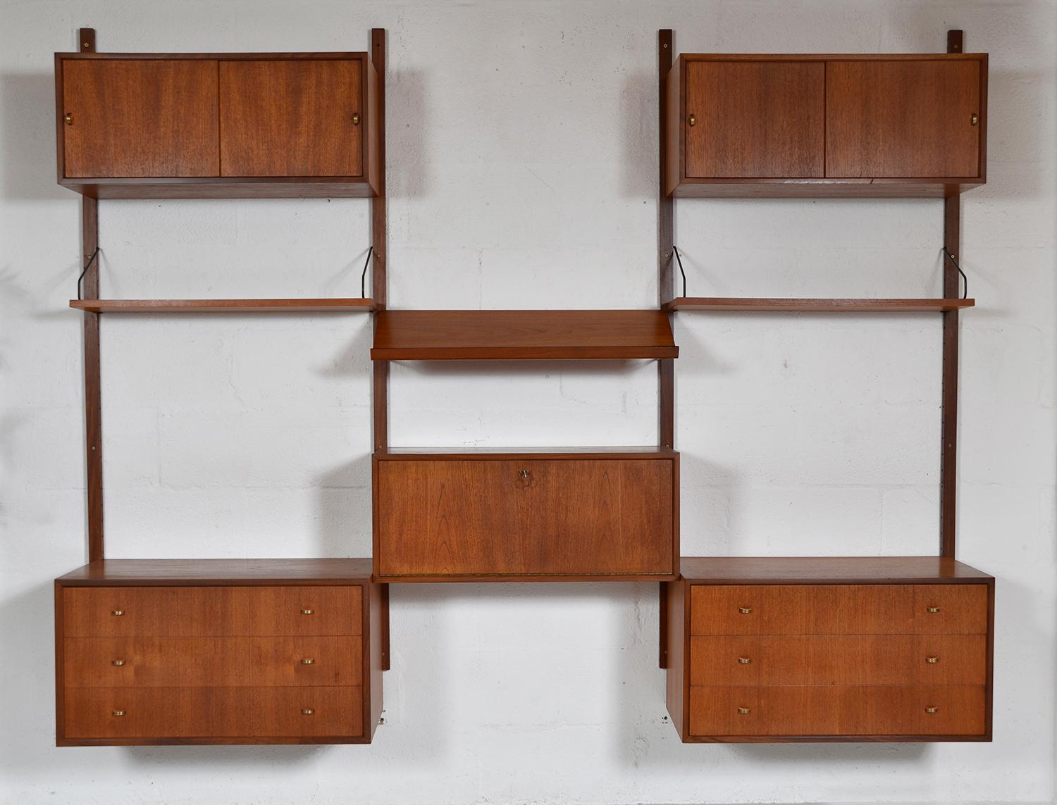 This highly versatile and functional “Royal System” was designed by Poul Cadovius in 1948. This particular piece is quintessentially Mid-century Modern being the first generation with orange-slice brass handles. 
Simply hung on brass pins and